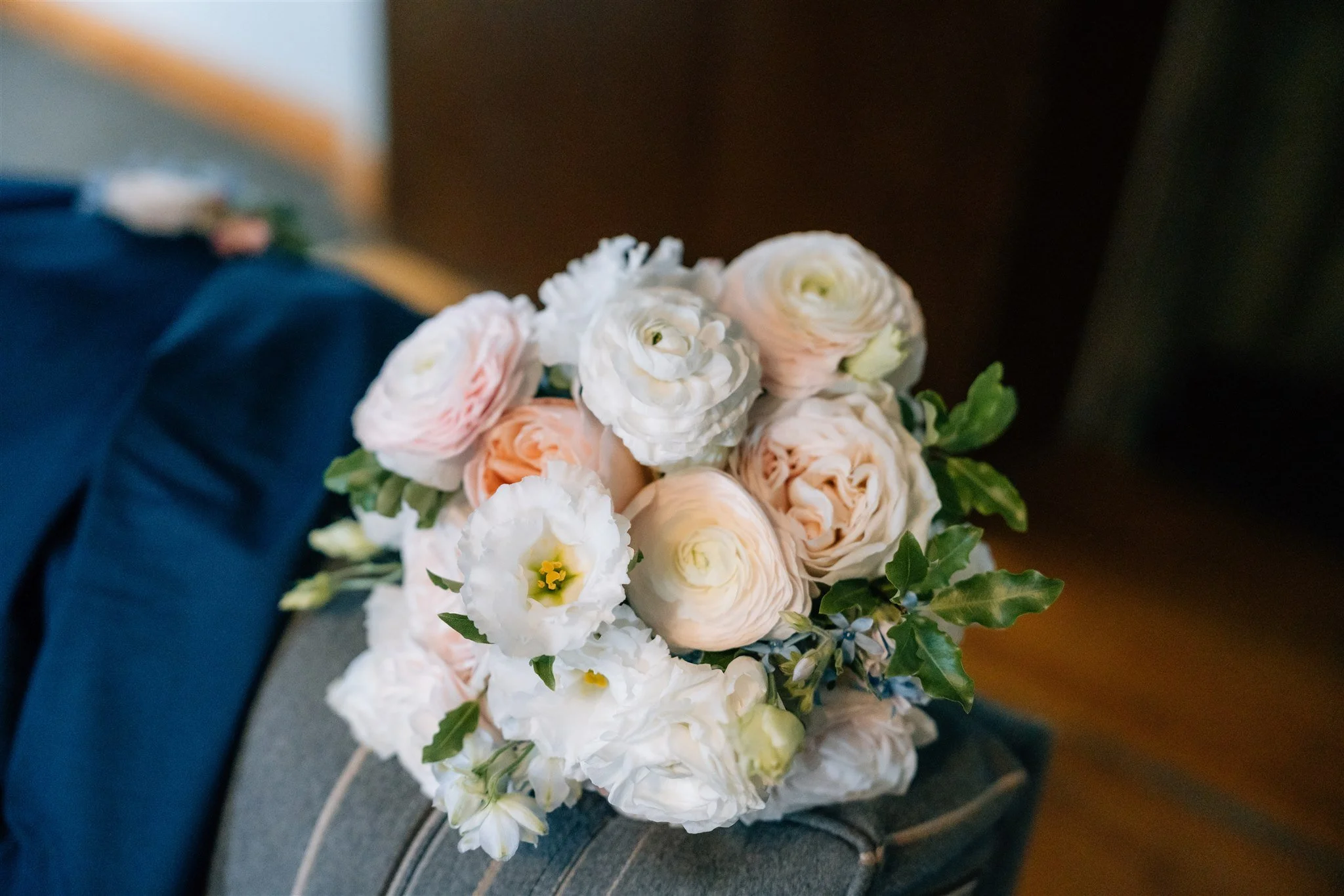 A bouquet of white and pale pink flowers with green leaves resting on a gray surface.