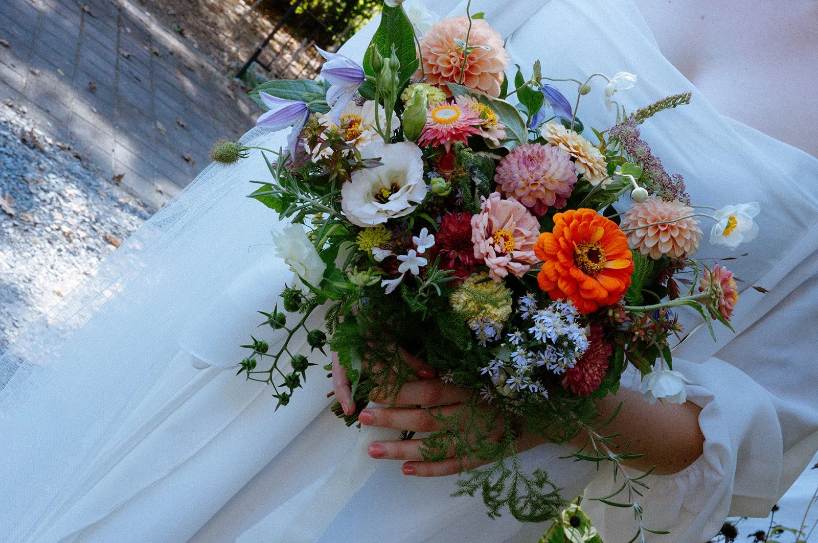 Person holding a colorful floral bouquet on a white cloth background.