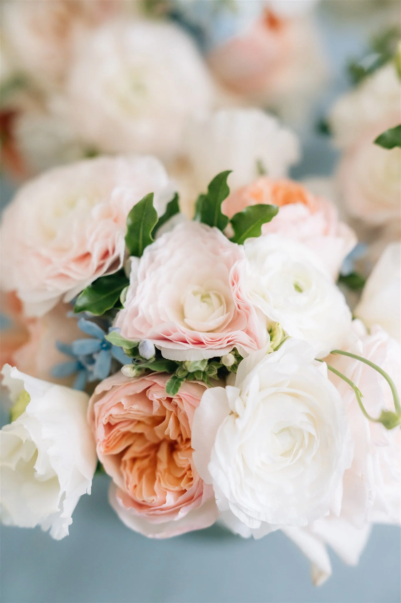 Close-up of a bouquet of pastel-colored roses and greenery with soft focus background.