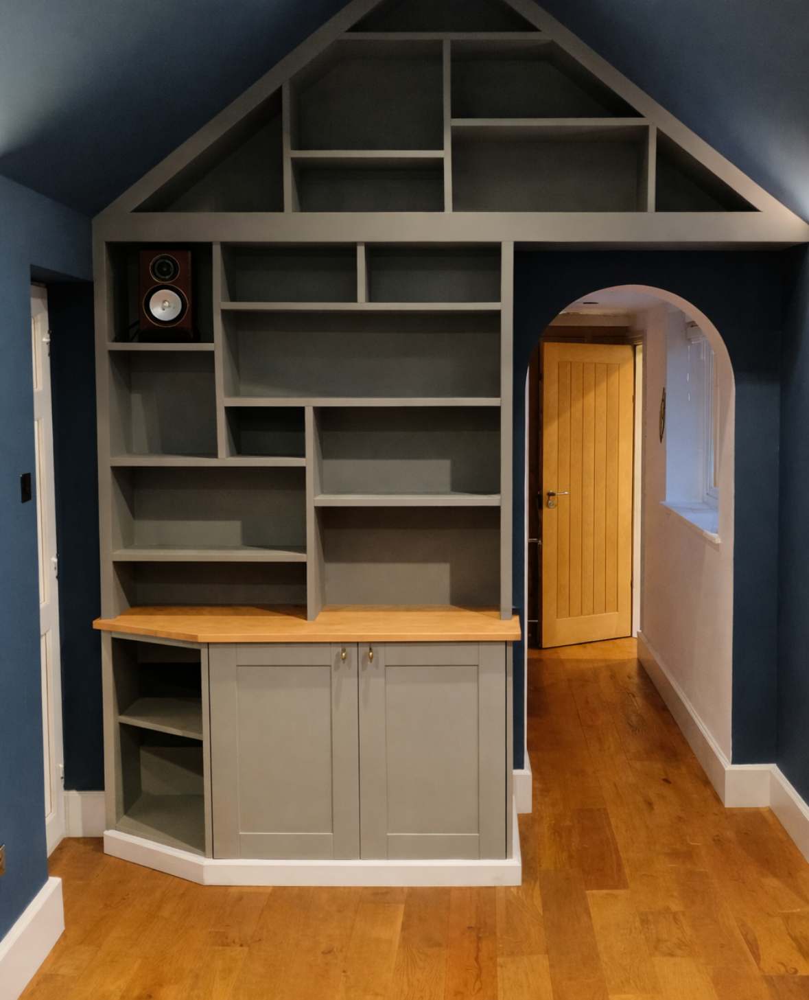 Grey shelving and cupboard unit surrounding doorway with vaulted ceiling