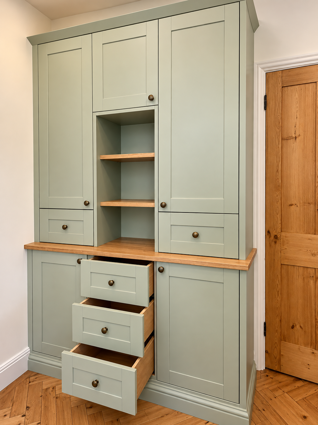 Sage green freestanding kitchen wall unit with open drawers