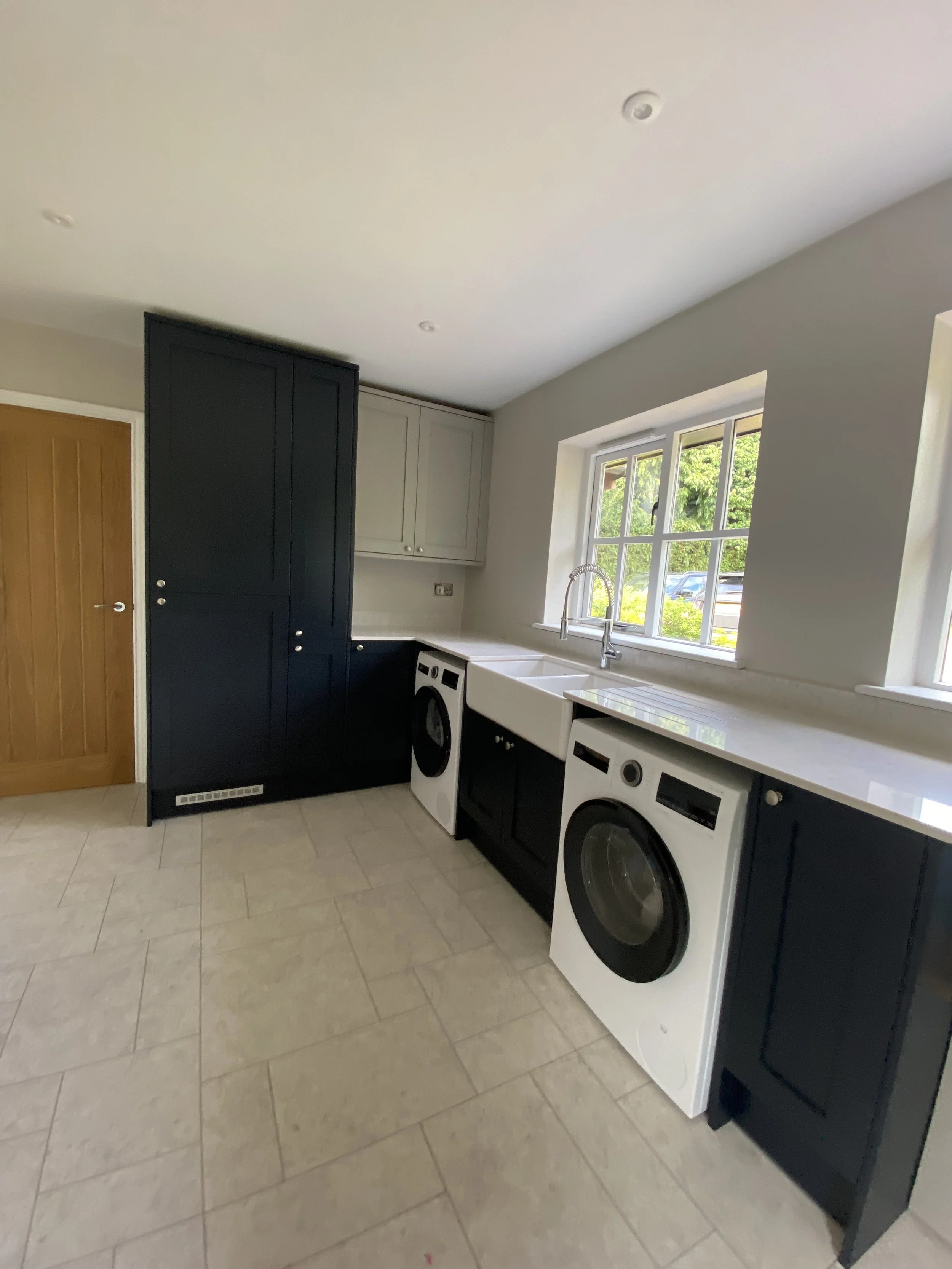 Utility room dark blue with tall cupboard and Belfast sink