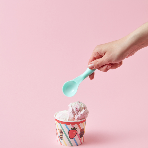 Hand greift mit Löffel in einen Becher Eis