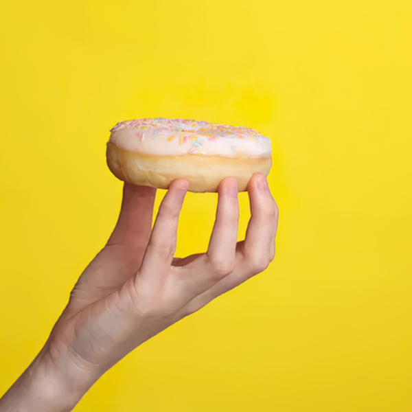 Hand hält einen Donut als Sinnbild für Heißhunger auf Süßes