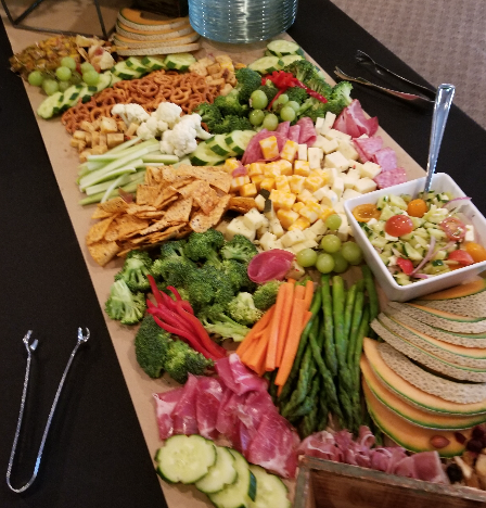 Assorted vegetables, cheeses, crackers, pasta, set up for a charcuterie grazing display.
