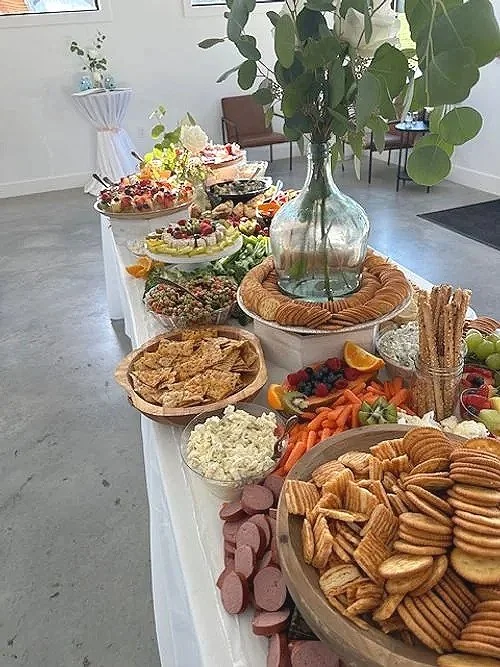 Grazing table display with fruit, vegetables, salad, sandwiches.
