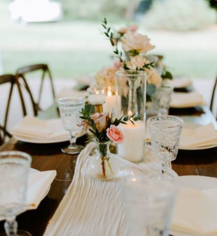 Elegant wedding tablescape with floral centerpiece, candles, glassware, and table settings