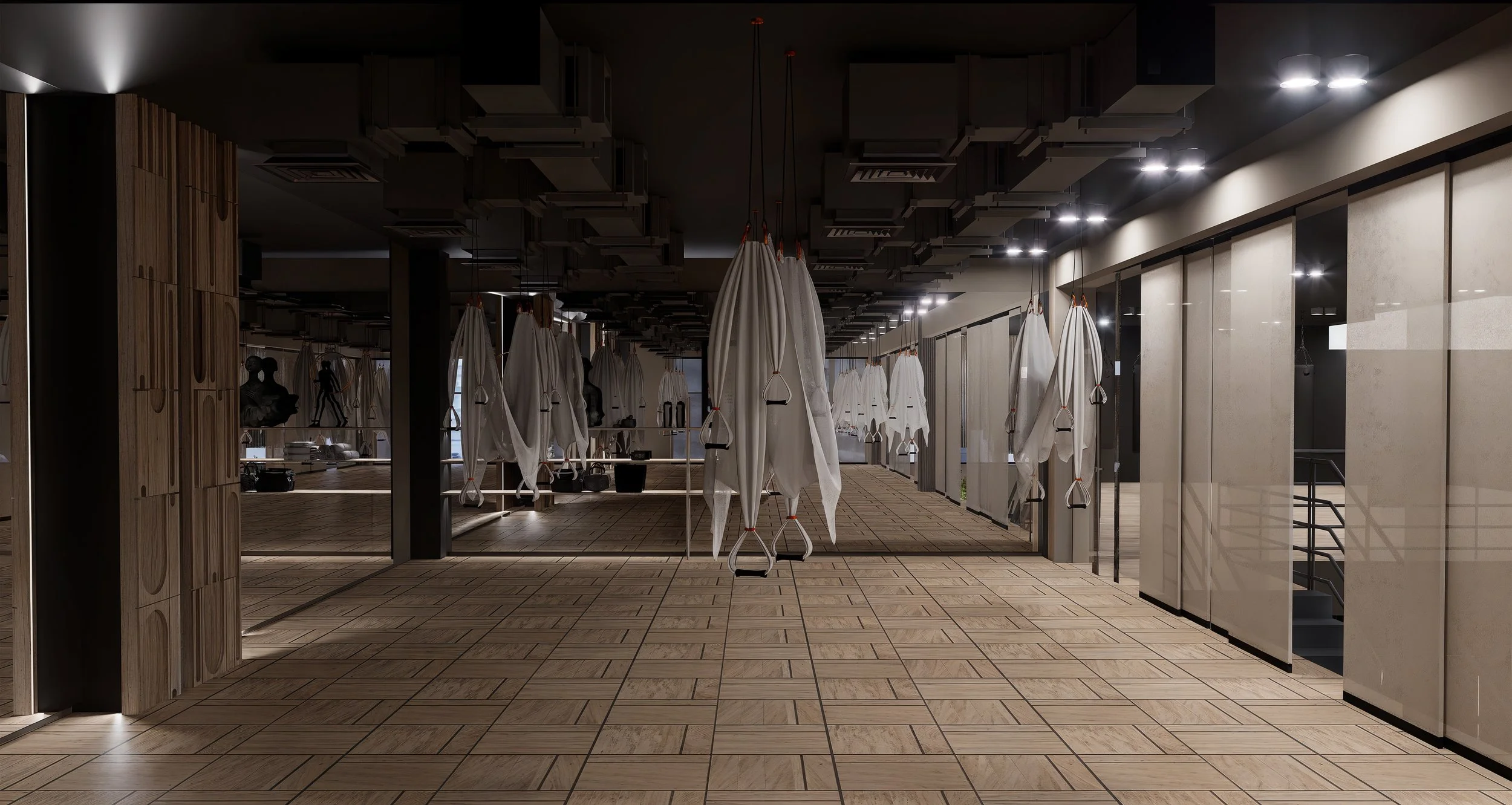 Empty gym with suspension training equipment hanging from the ceiling, wooden flooring, large windows with blinds, and a mirror wall.