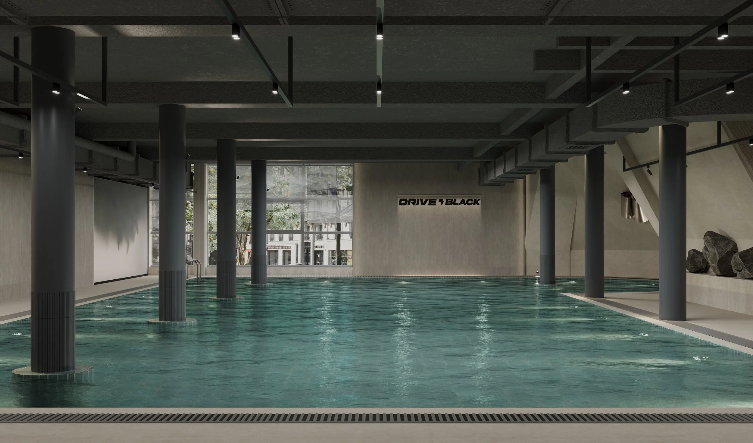 Indoor pool area with large windows, gray pillars, and a sign that reads "Drive Black" on the wall.