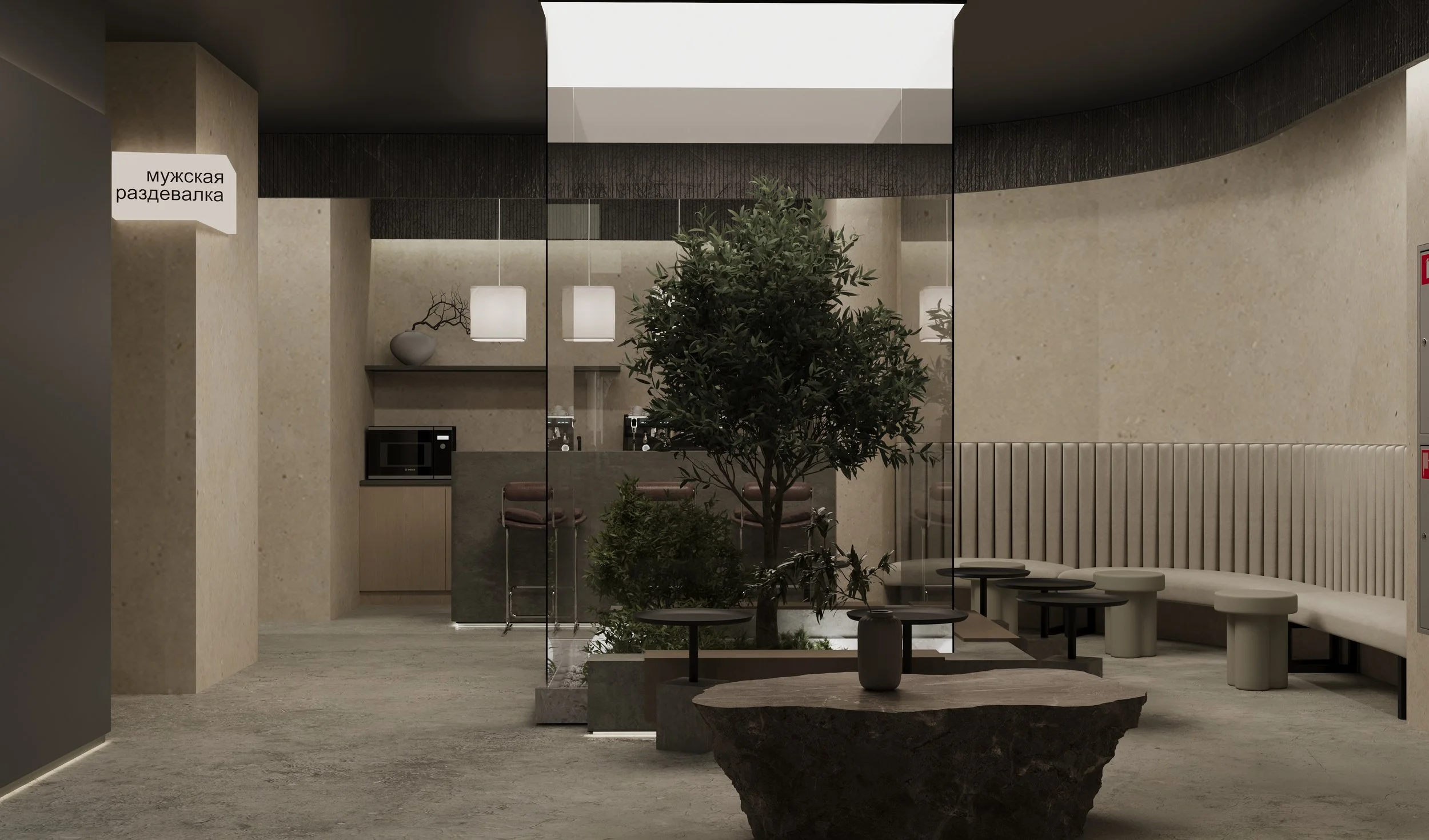 Modern lobby or waiting area with beige walls, a large indoor tree in a stone planter, and a curved beige bench with small tables. Kitchen area visible in the background with a microwave, barstools, and pendant lighting.