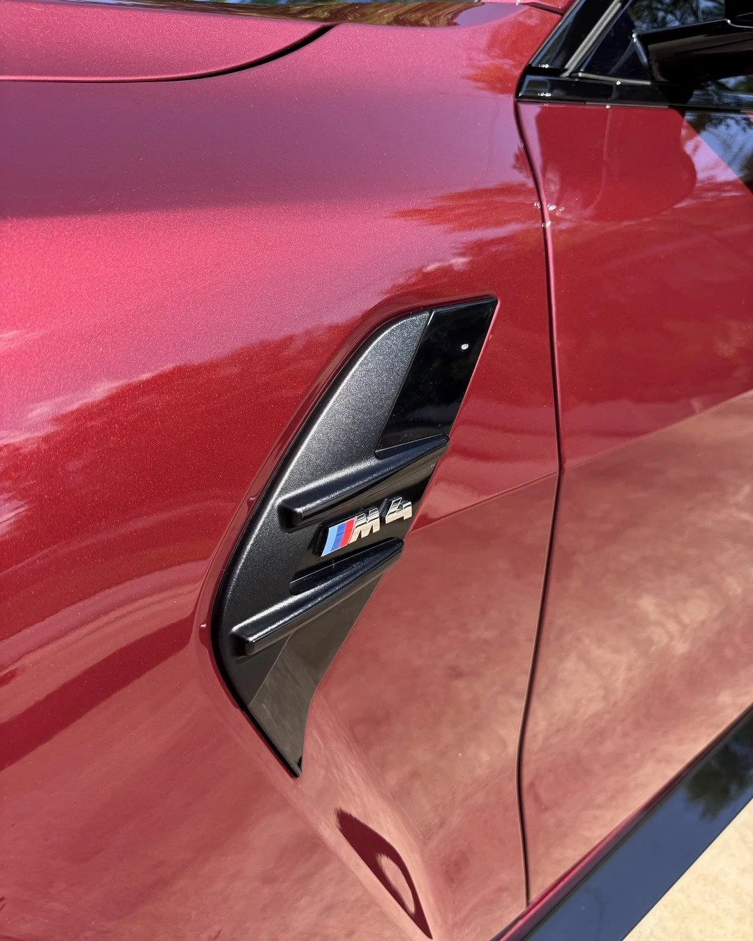 BMW M4 Competition badge and red paint after a mobile Deluxe Detail in Homewood, Alabama.