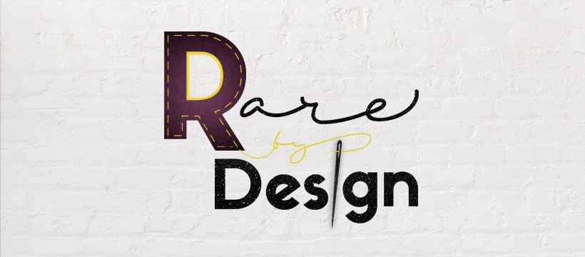 Decorative wall sign with the words "Rare by Design" in different fonts and styles, mounted on a white brick wall.