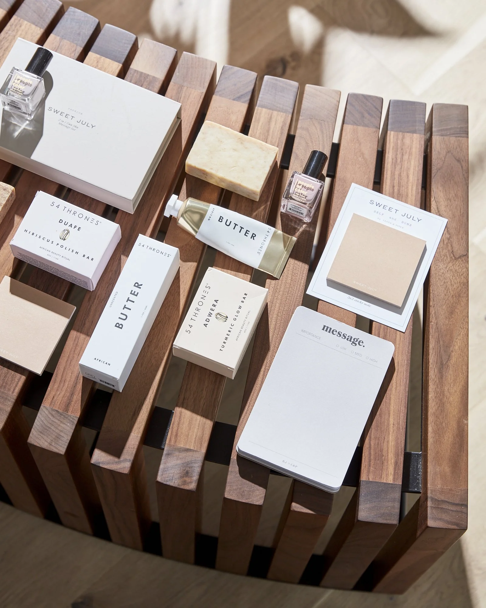A wooden table with various skincare and beauty products, including soap, lotion, nail polish, and small boxes and cards arranged on it.