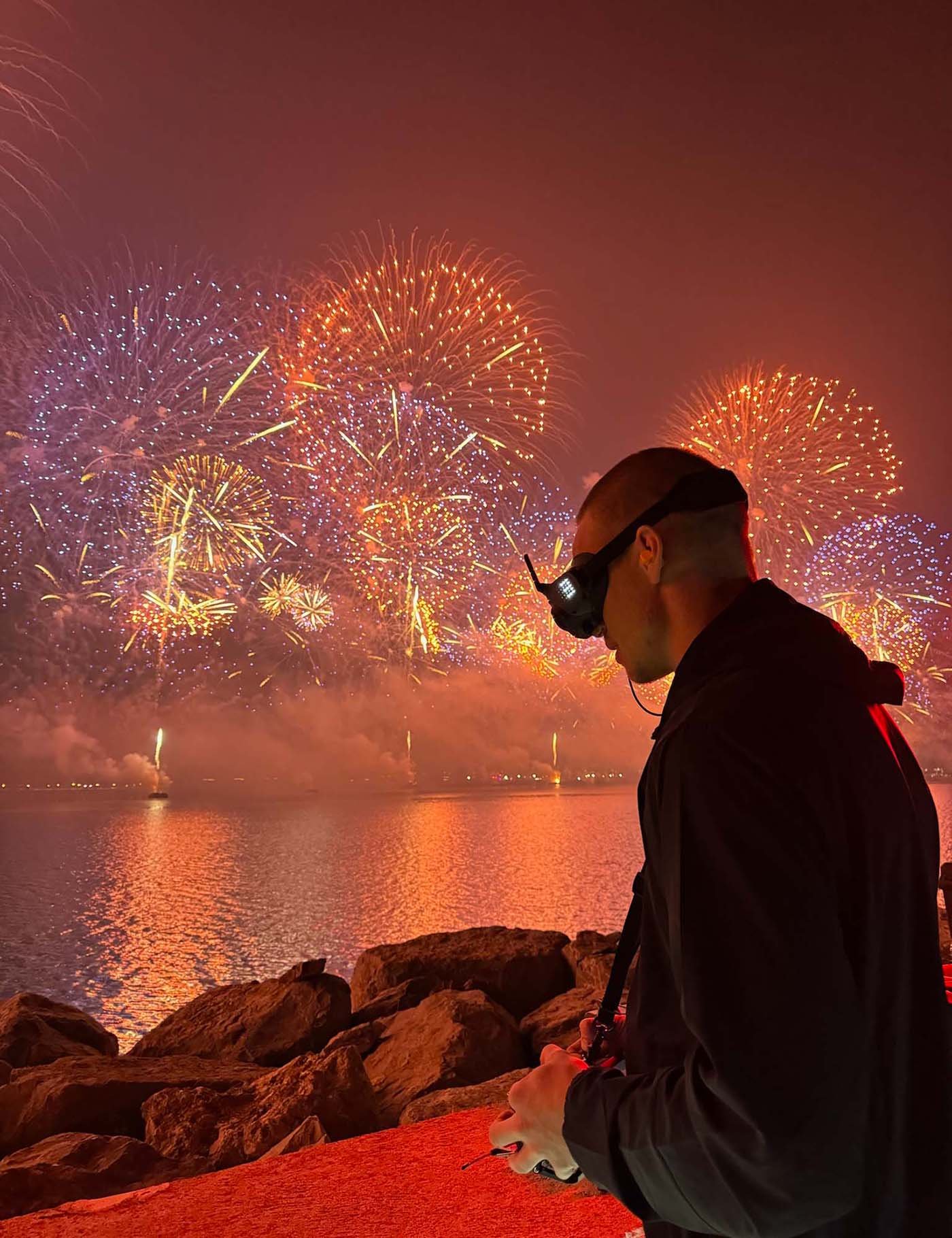  Drone operator controlling a drone amidst vibrant fireworks display. 