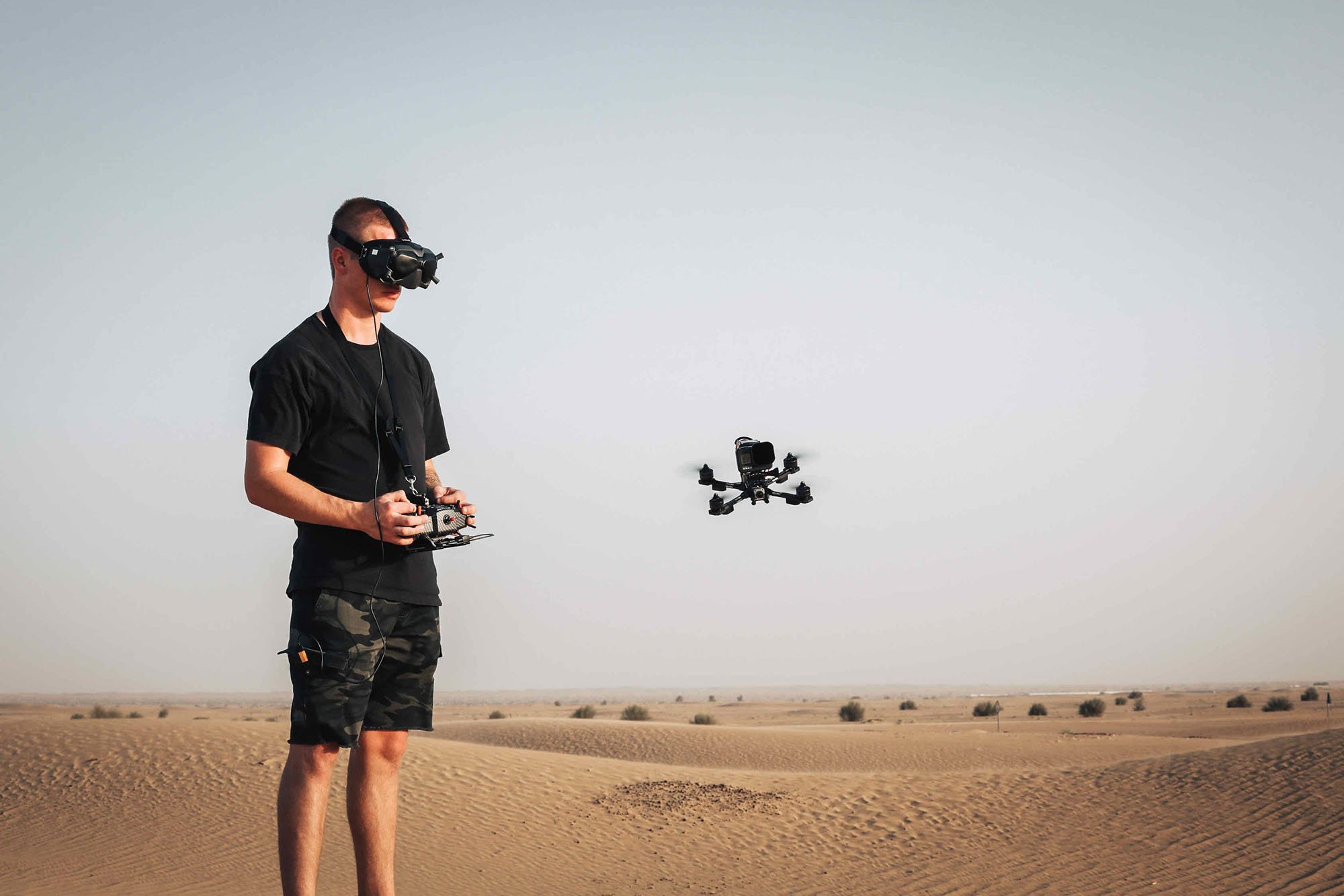 Operador de dron pilotando un dron en un vasto paisaje desértico.