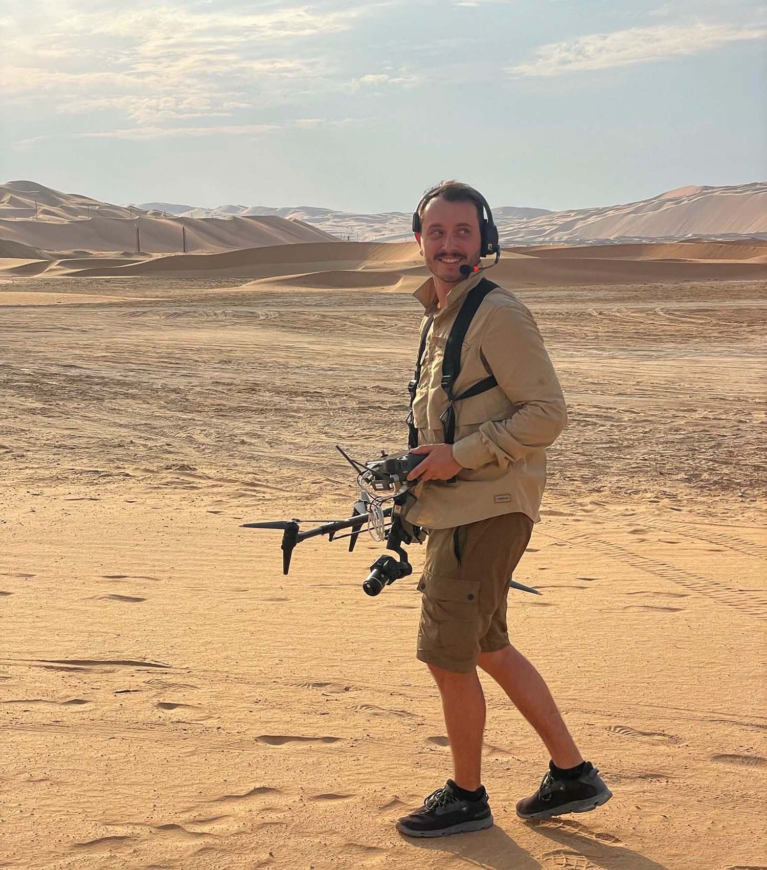  Operador de dron sosteniendo un dron en un vasto paisaje desértico. 