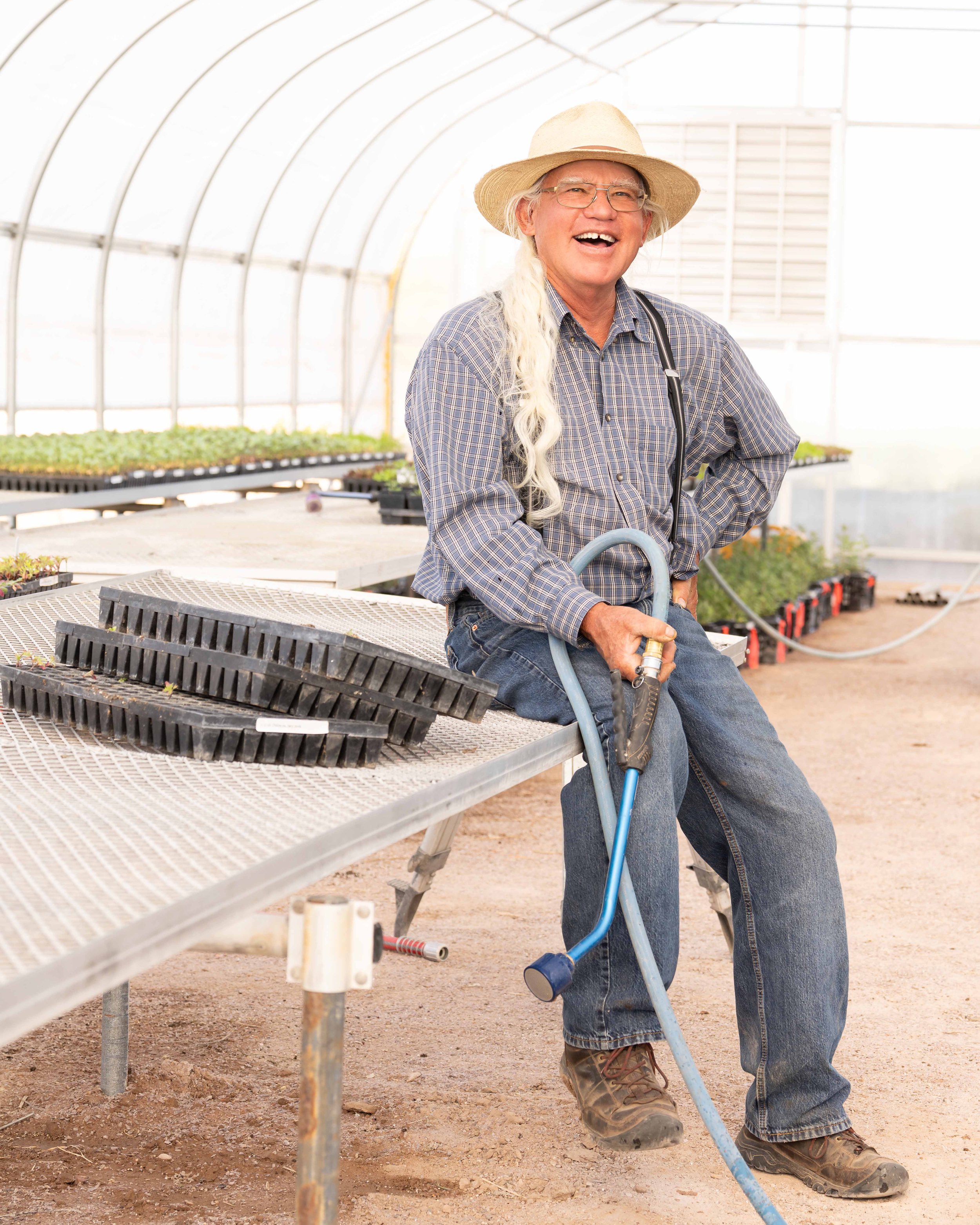 man holding garden hose in greenhouse