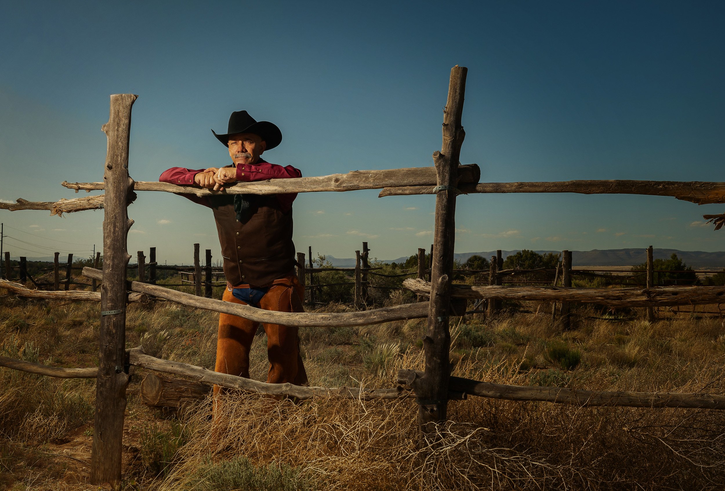Portrait of Pony Express re-enactor standing next to a split rail fence