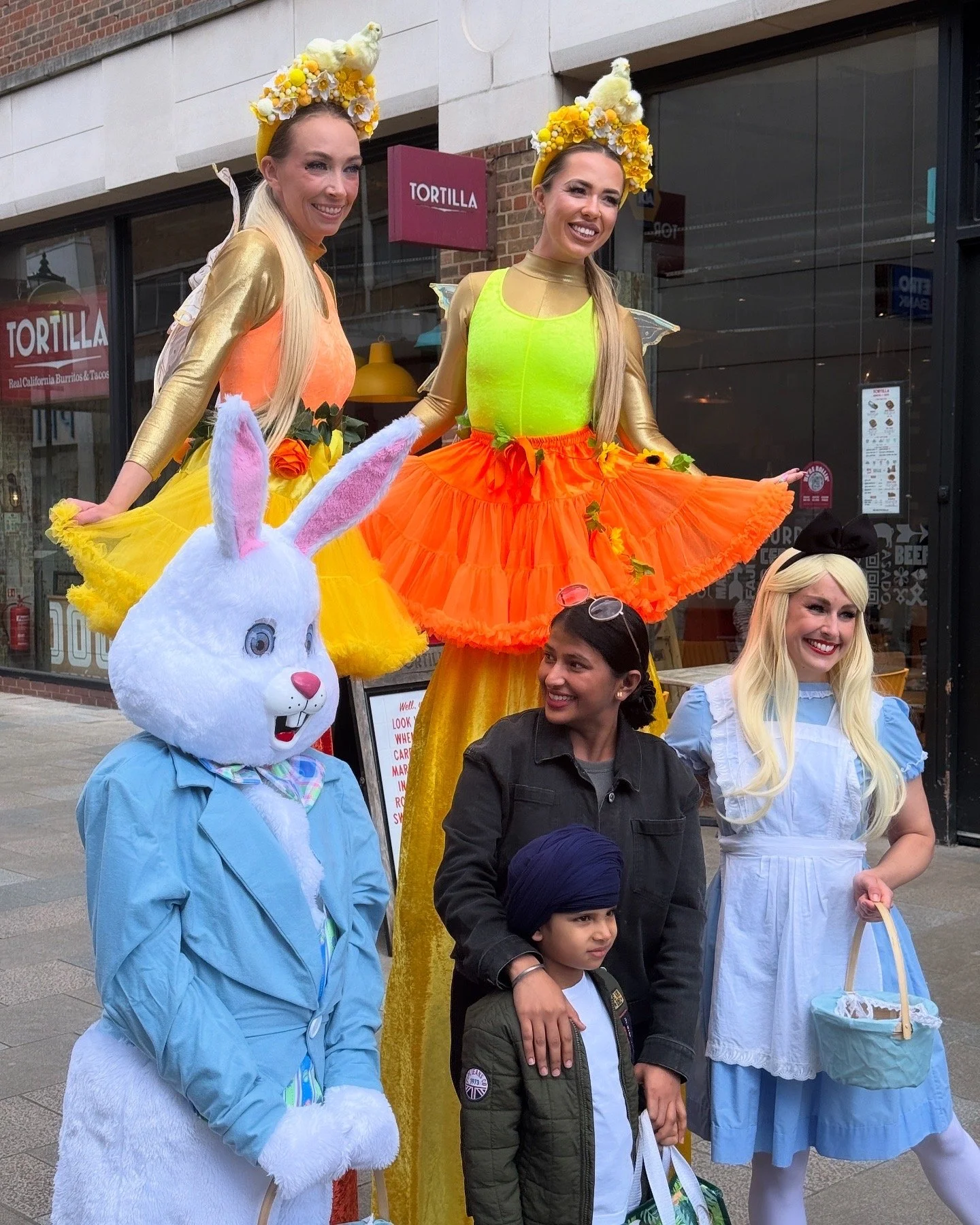 Easter bunny mascot, Alice in Wonderland, Stilt walking Easter Fairies posing with people on Watford High Street for their easter event 