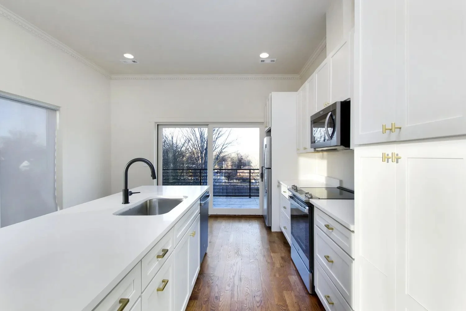 A bright modern kitchen with white cabinetry, stainless appliances, and an island built in a new duplex home at 1917 Holly Street.