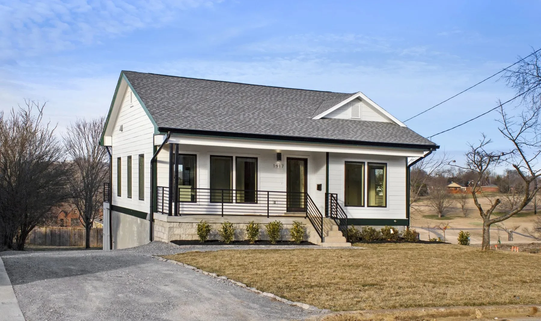 Wide-angle exterior view of a newly built custom duplex residence featuring modern black railings, white fiber cement siding, and a nicely landscaped front yard on Holly Street.