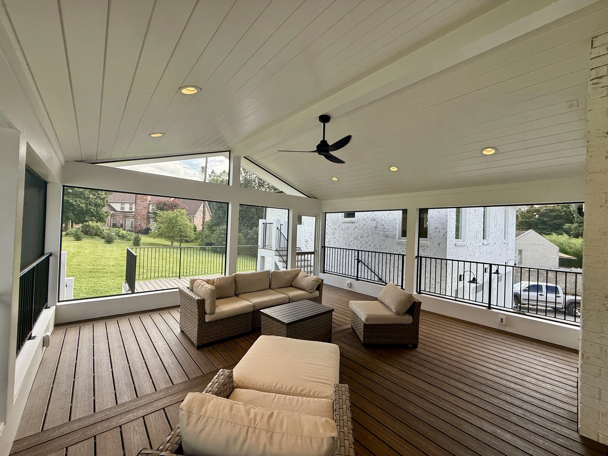 Spacious screened porch with vaulted ceiling, recessed lighting, and outdoor seating overlooking the backyard in West Meade.