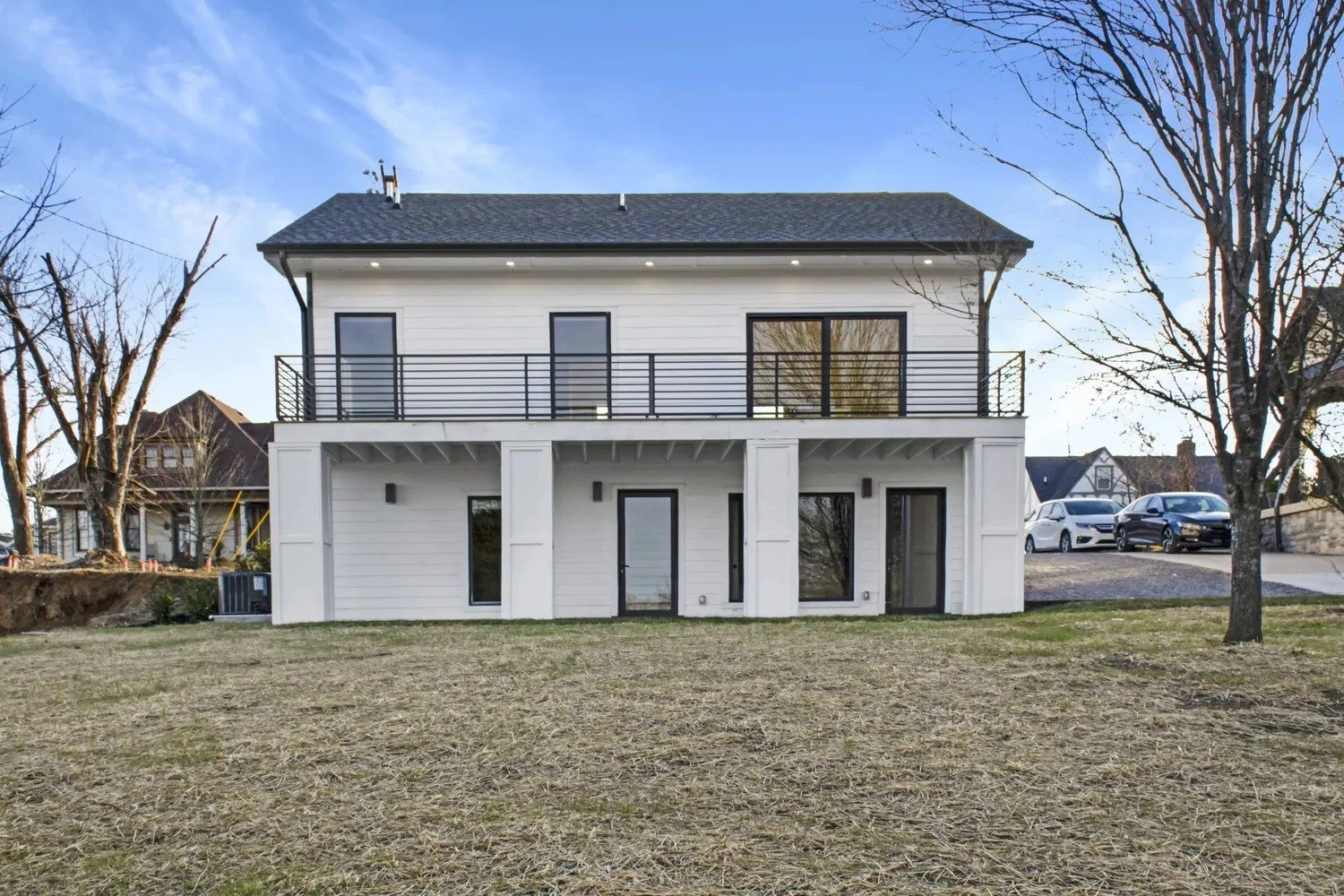 Large elevated deck and patio with black metal railing overlooking the surrounding landscape and large backyard at a custom duplex home on Holly Street.