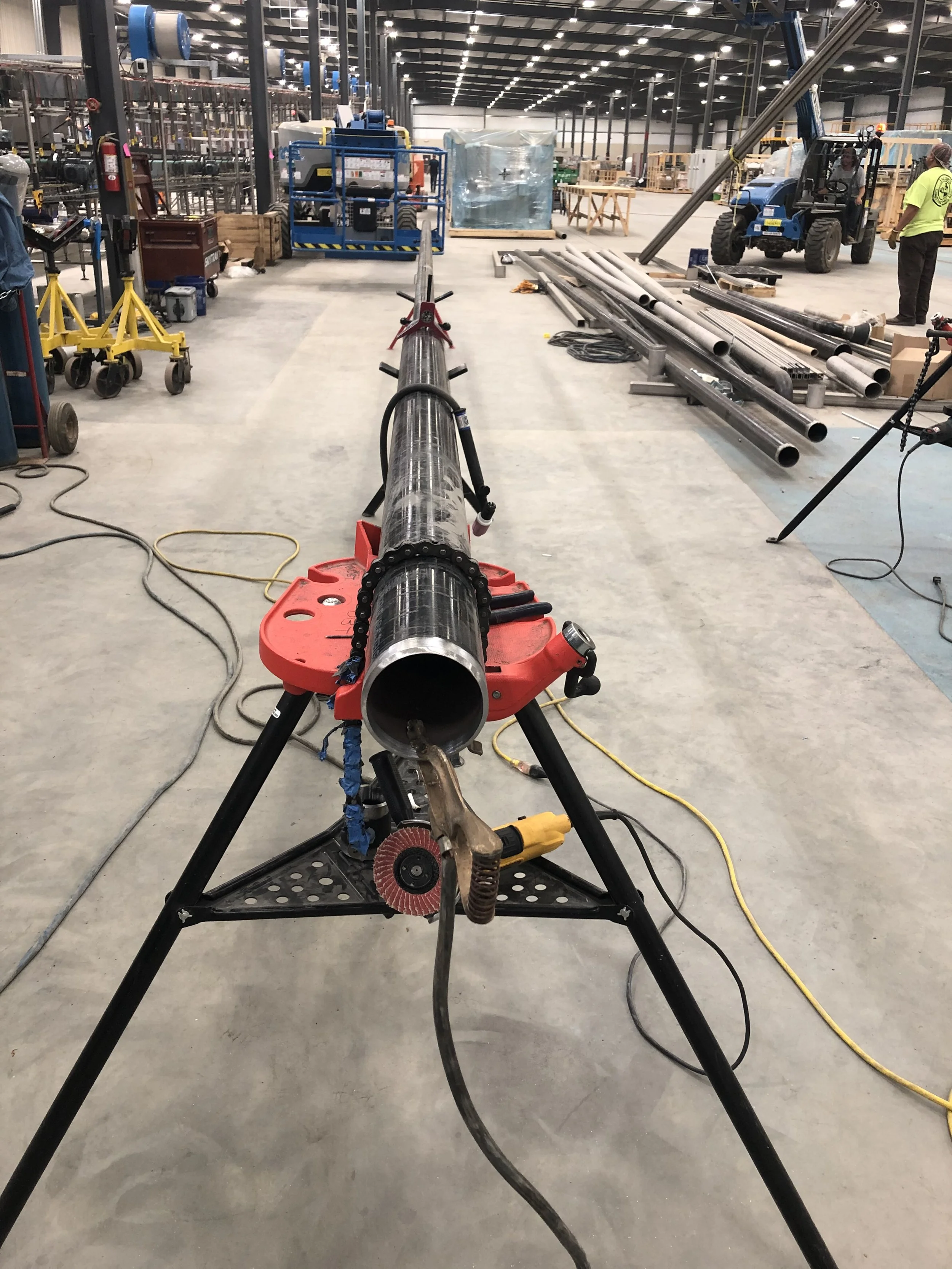 Industrial pipe fabrication and fit-up on pipe stands inside a manufacturing facility.