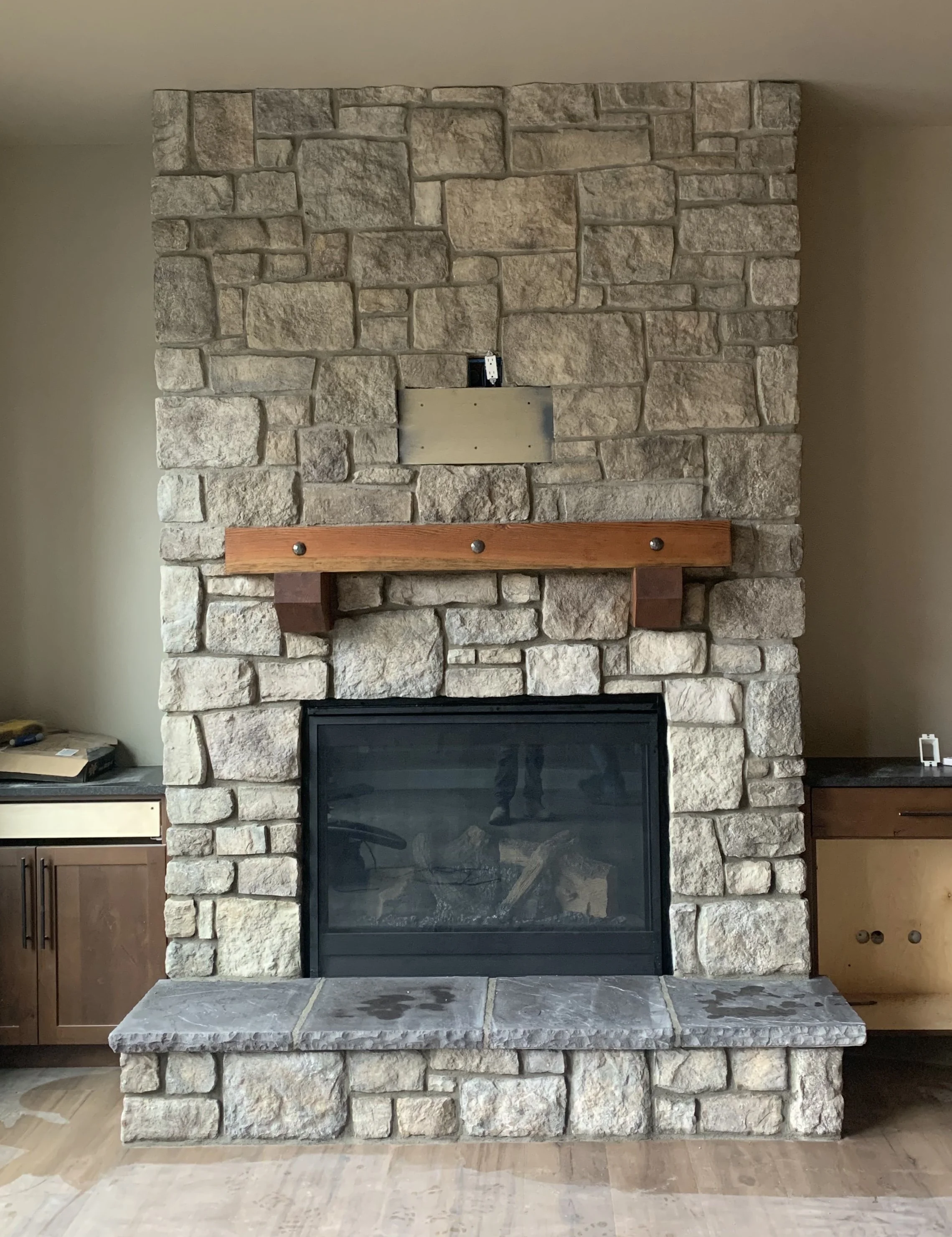 Stone fireplace with a wooden mantel and a stone hearth in a living room.