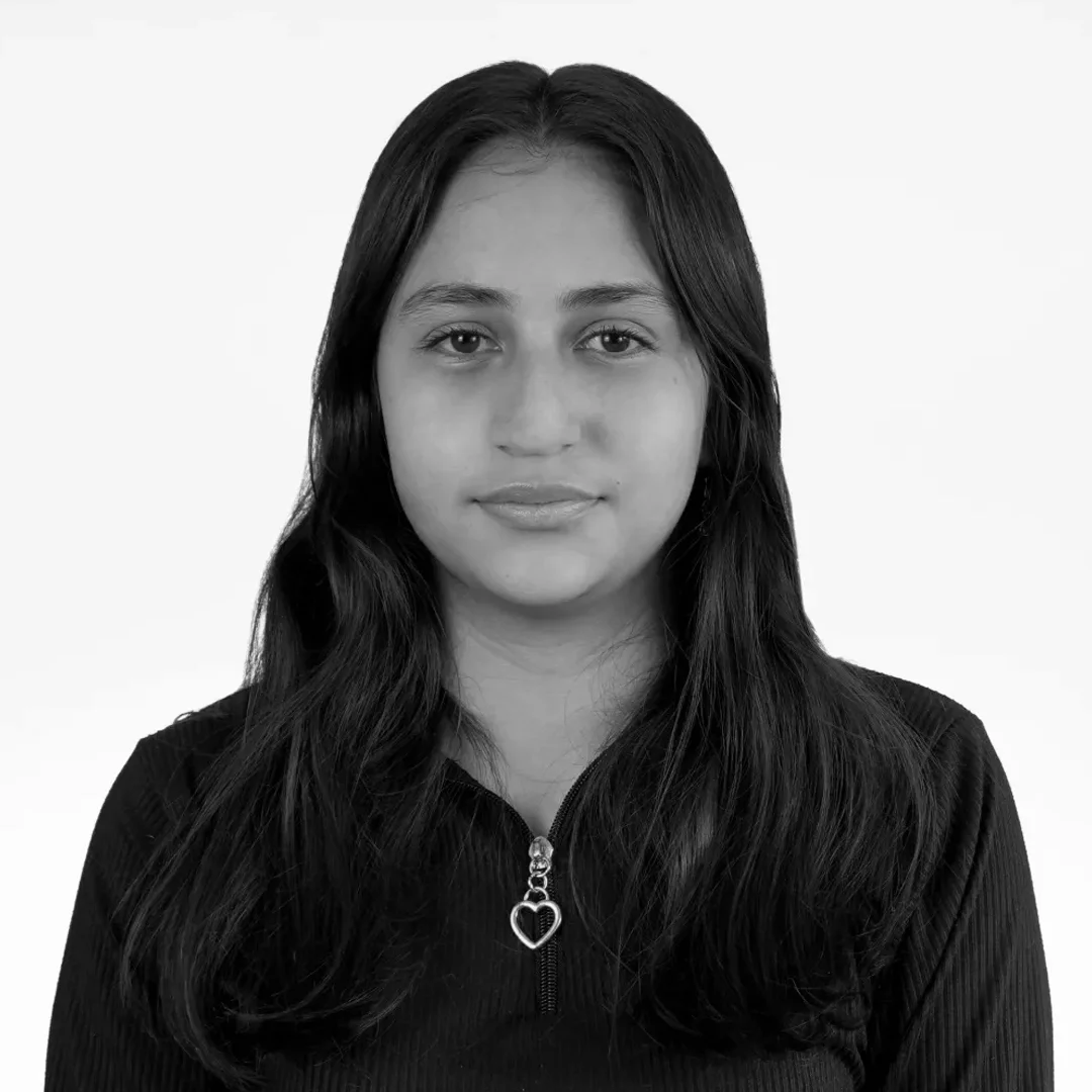 Retrato en blanco y negro de una mujer joven con gafas, cabello largo y liso, con una sonrisa y vestimenta casual.