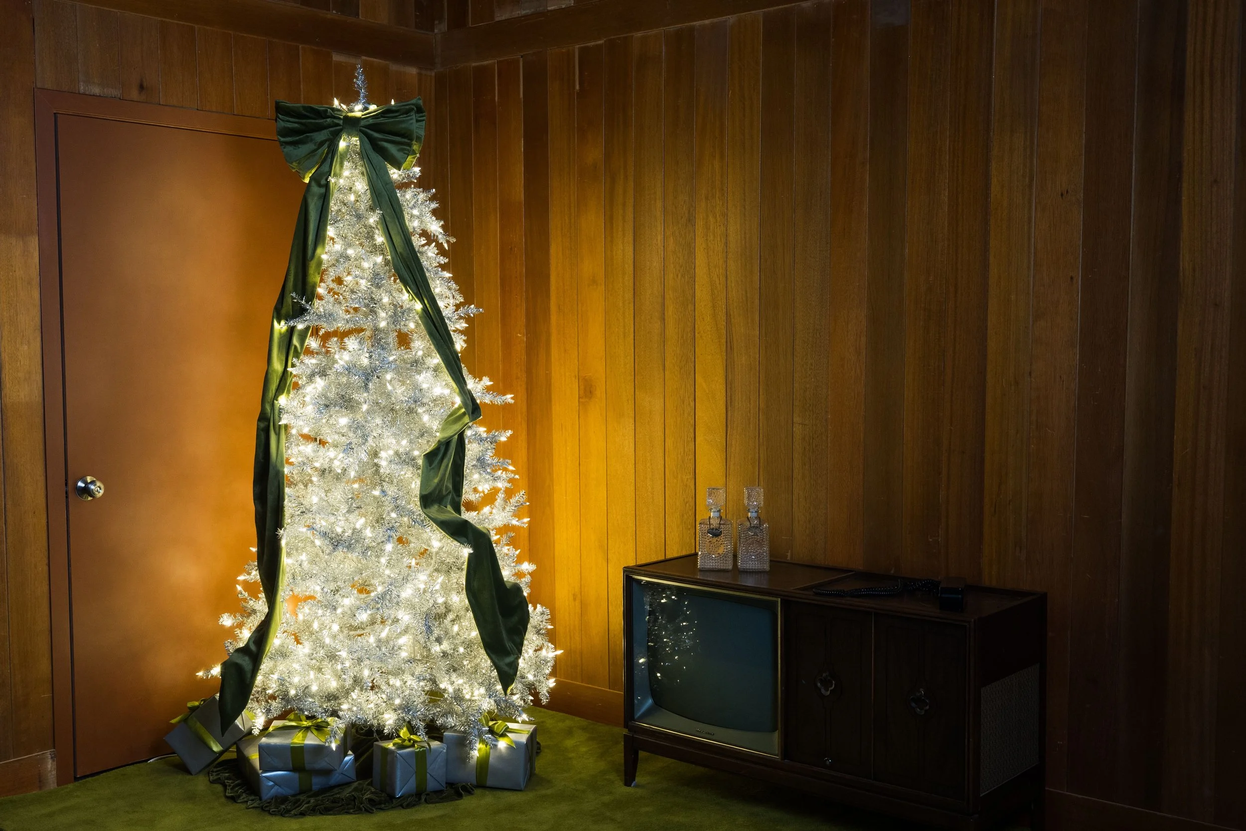 Silver Mid Century Modern Christmas Tree and Vintage Television in front of a wood wall. 