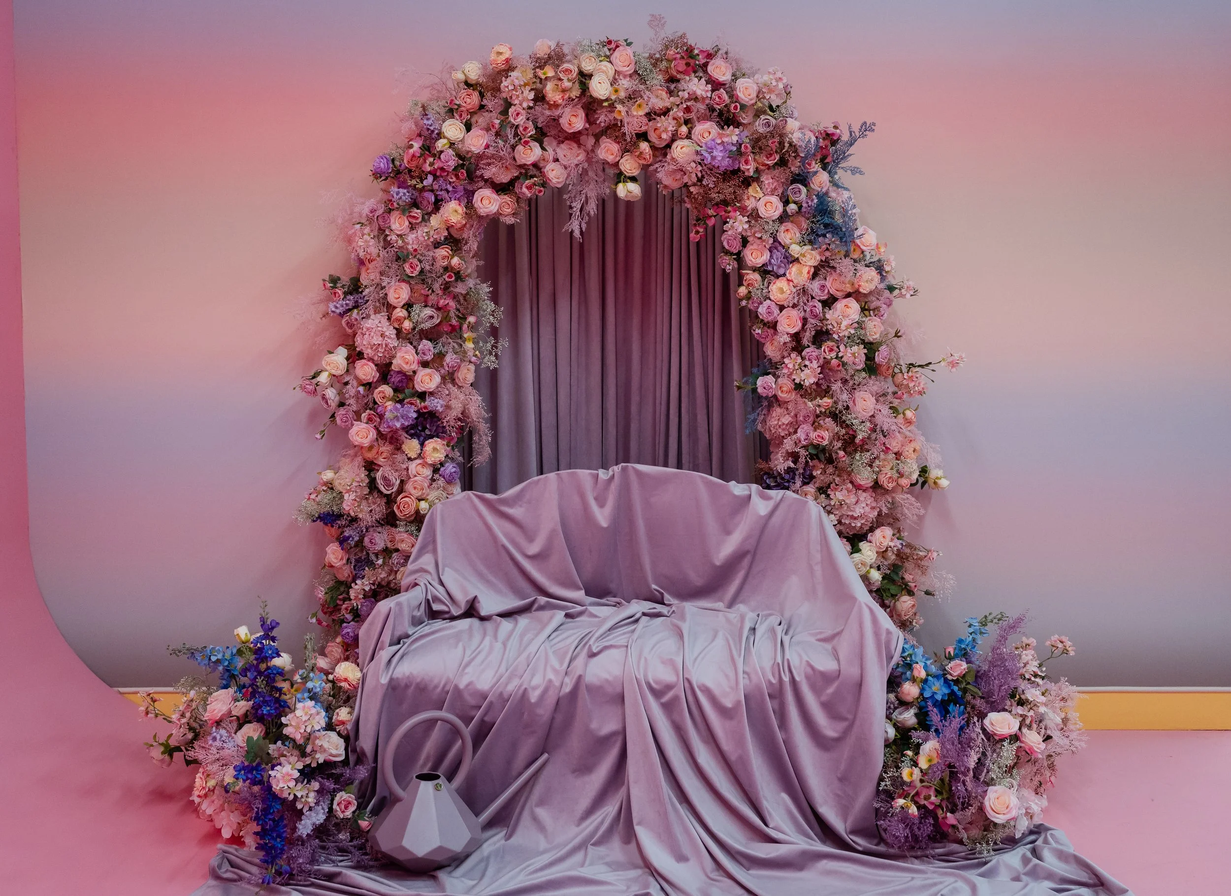 A big red wooden heart set piece with arrows piercing it, set against a pink background.