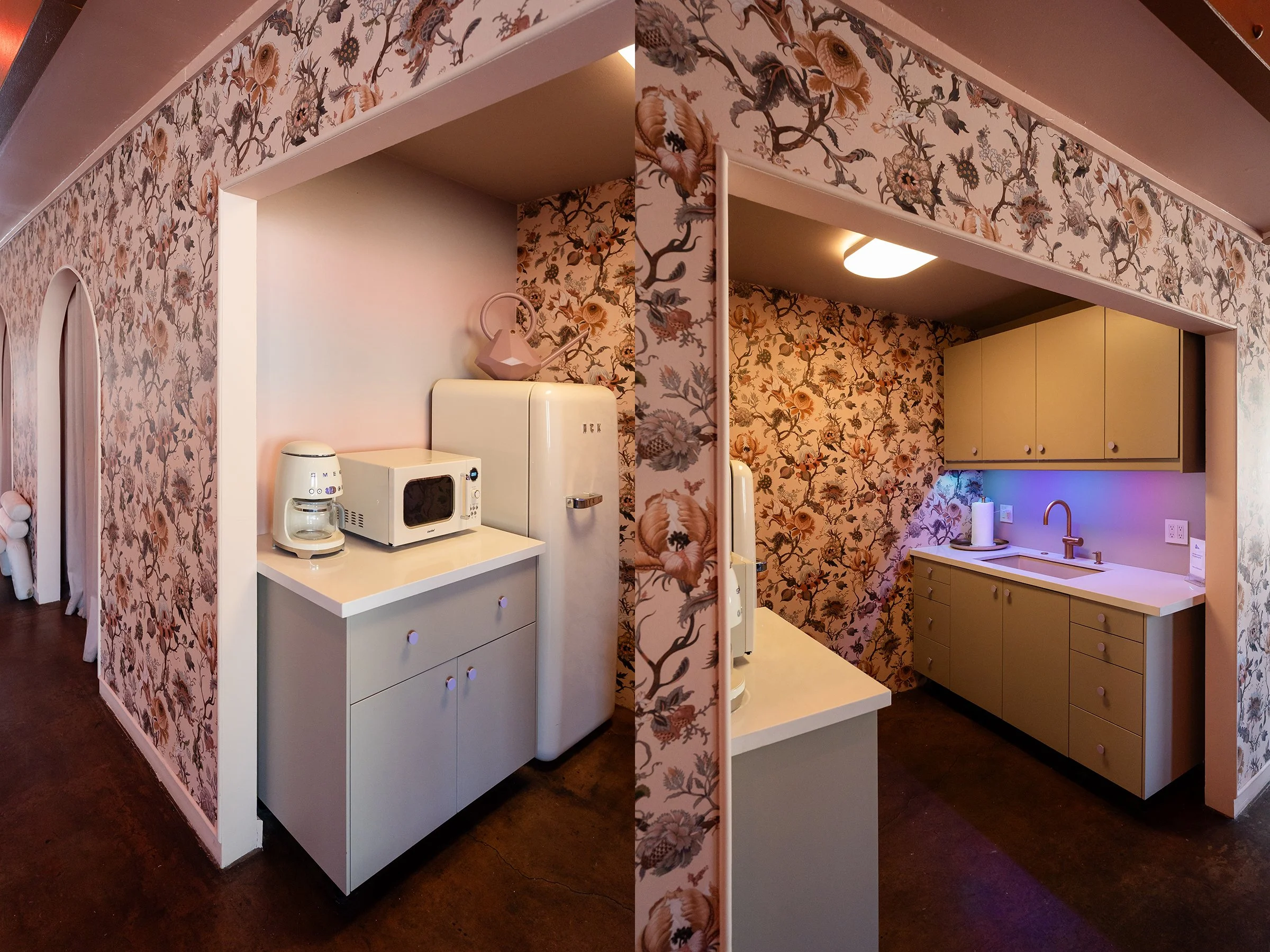 A small kitchenette area with floral wallpaper, a white microwave and coffee maker on a white counter, and yellow cabinets above the sink. A pink watering can is on top of a vintage refrigerator.