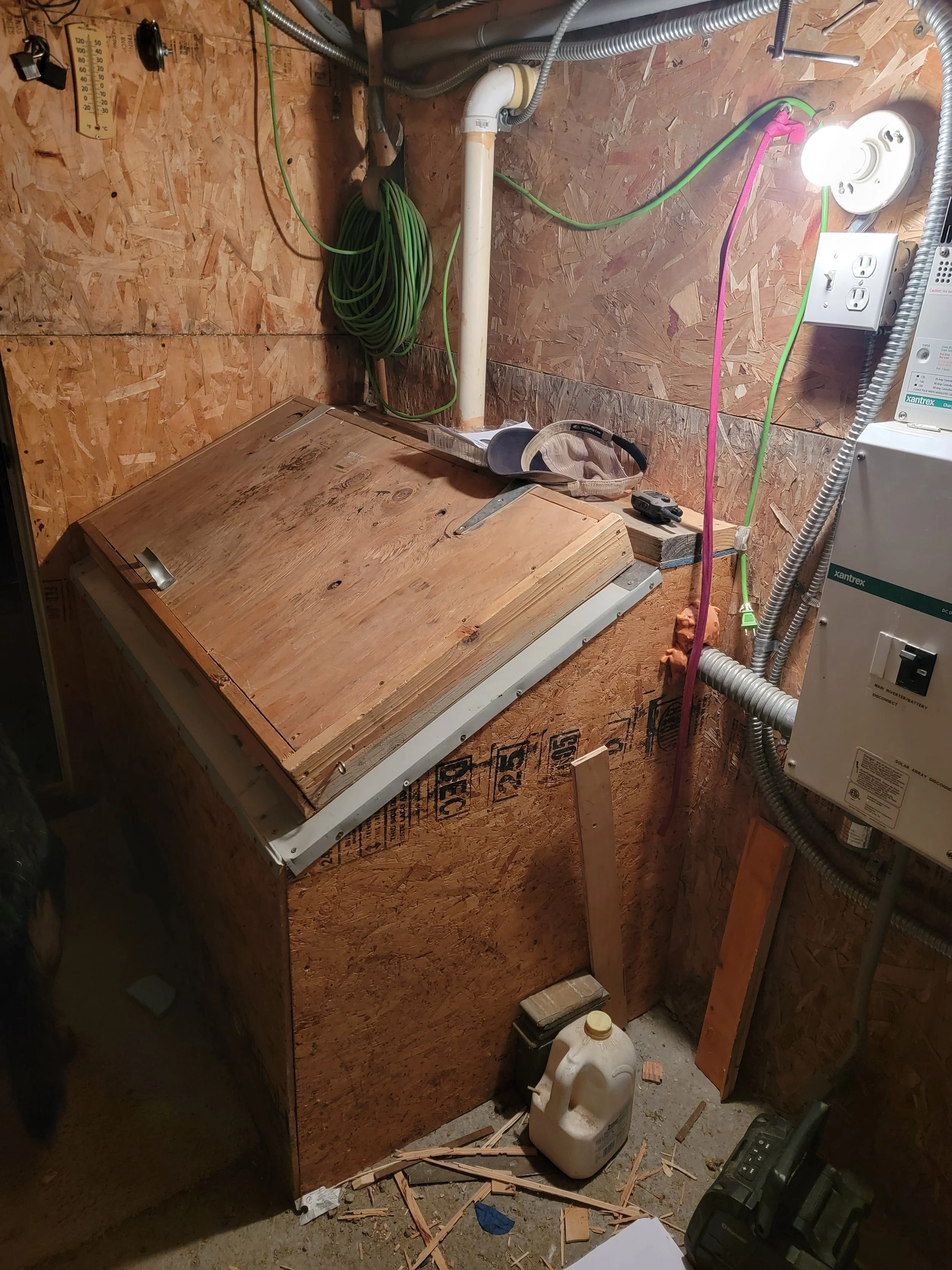 Laundry room with wooden cabinet, green garden hose, electrical cords, and tools.