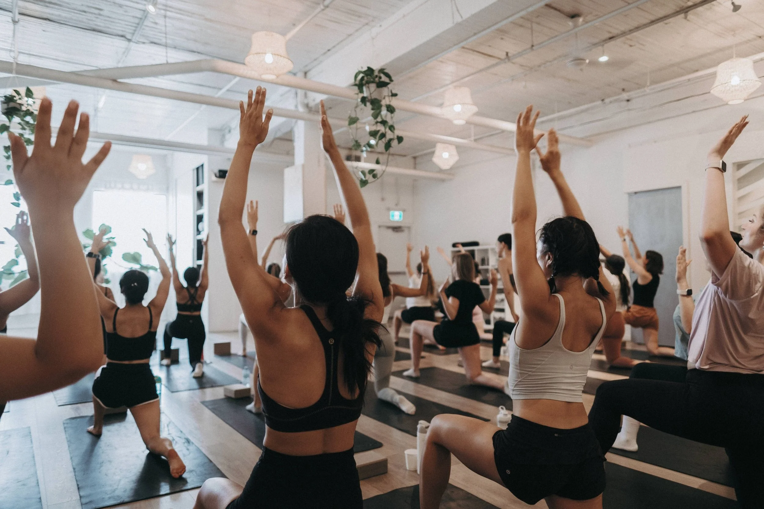 group stretching class in a bright studio, women performing a deep lunge exercise