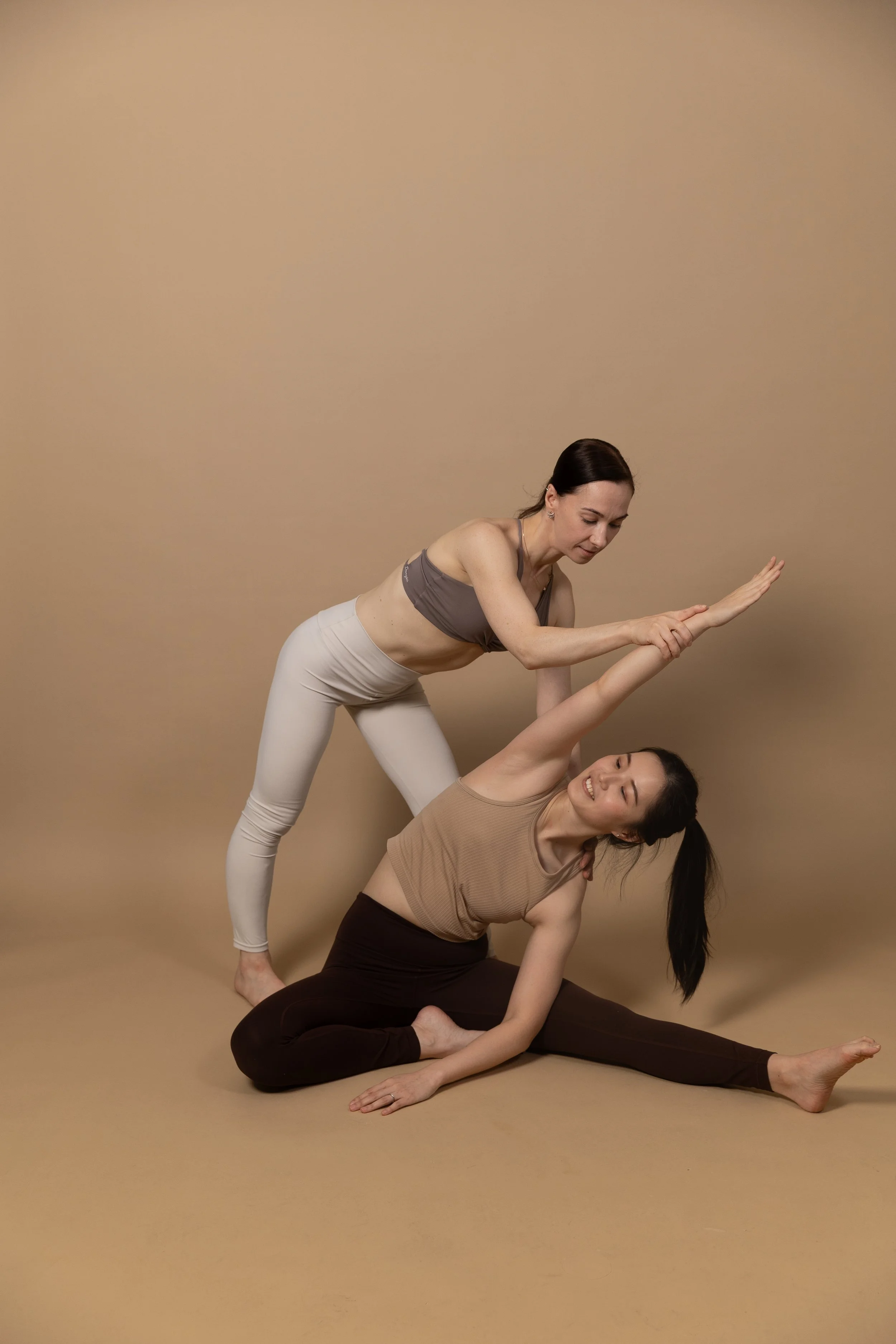 instructor doing hands on adjustment on student in stretching class