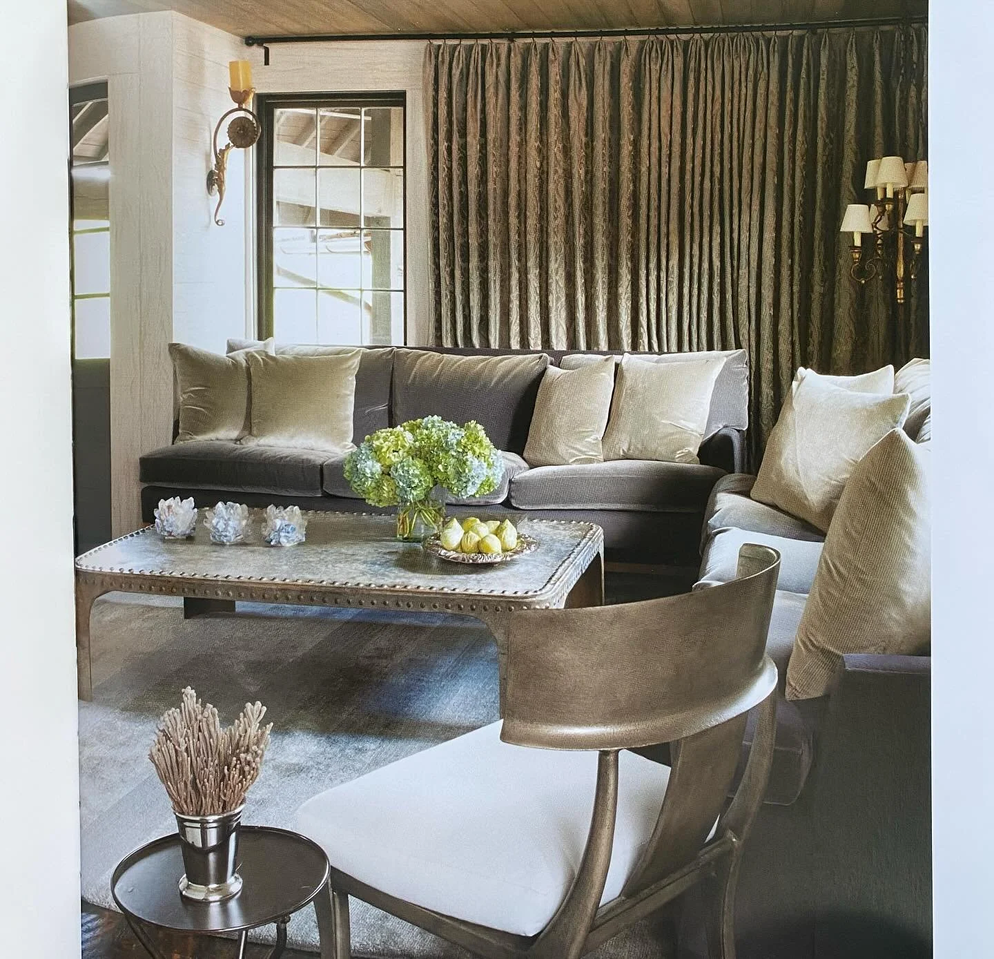 &ldquo;A metal table made from fragments of an industrial container and a sleek steel klismos chair owe nothing to organic form or material. But the fiddlehead-shaped sconce and plant-like pattern of the damask curtains bring indirect quotations of t