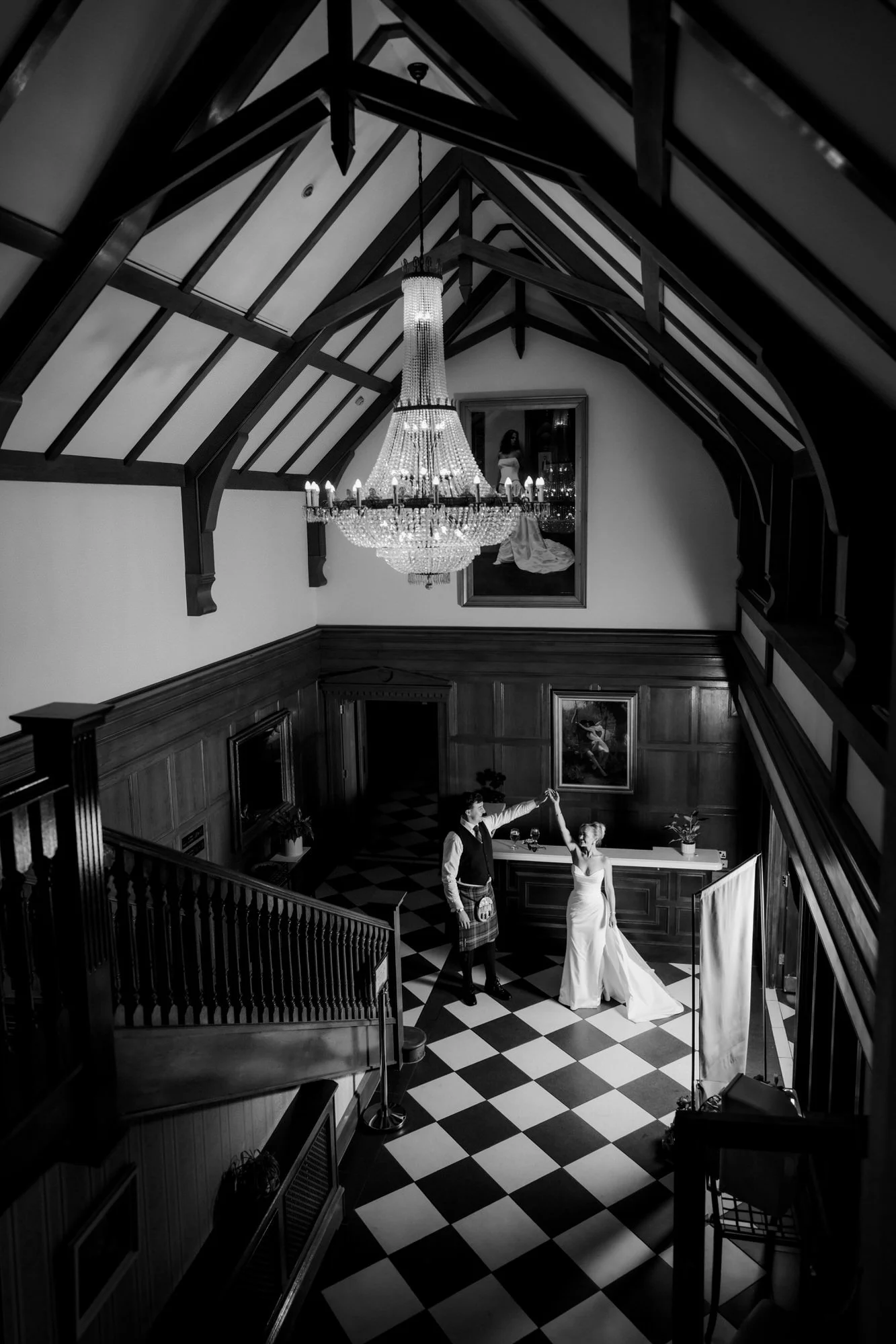 Black and white portrait of Fiona and Connor beneath Lochgreen’s chandelier.