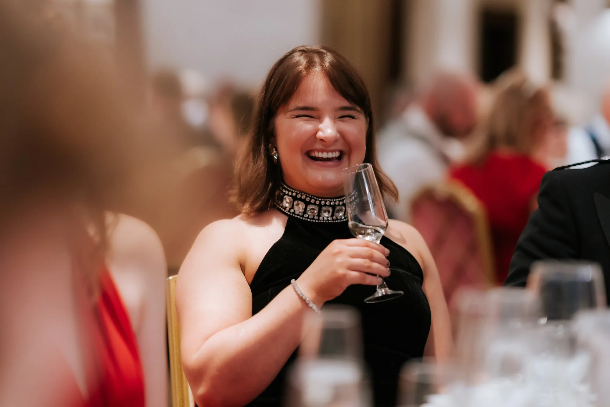 Wedding guest laughing with a champagne glass in her hand