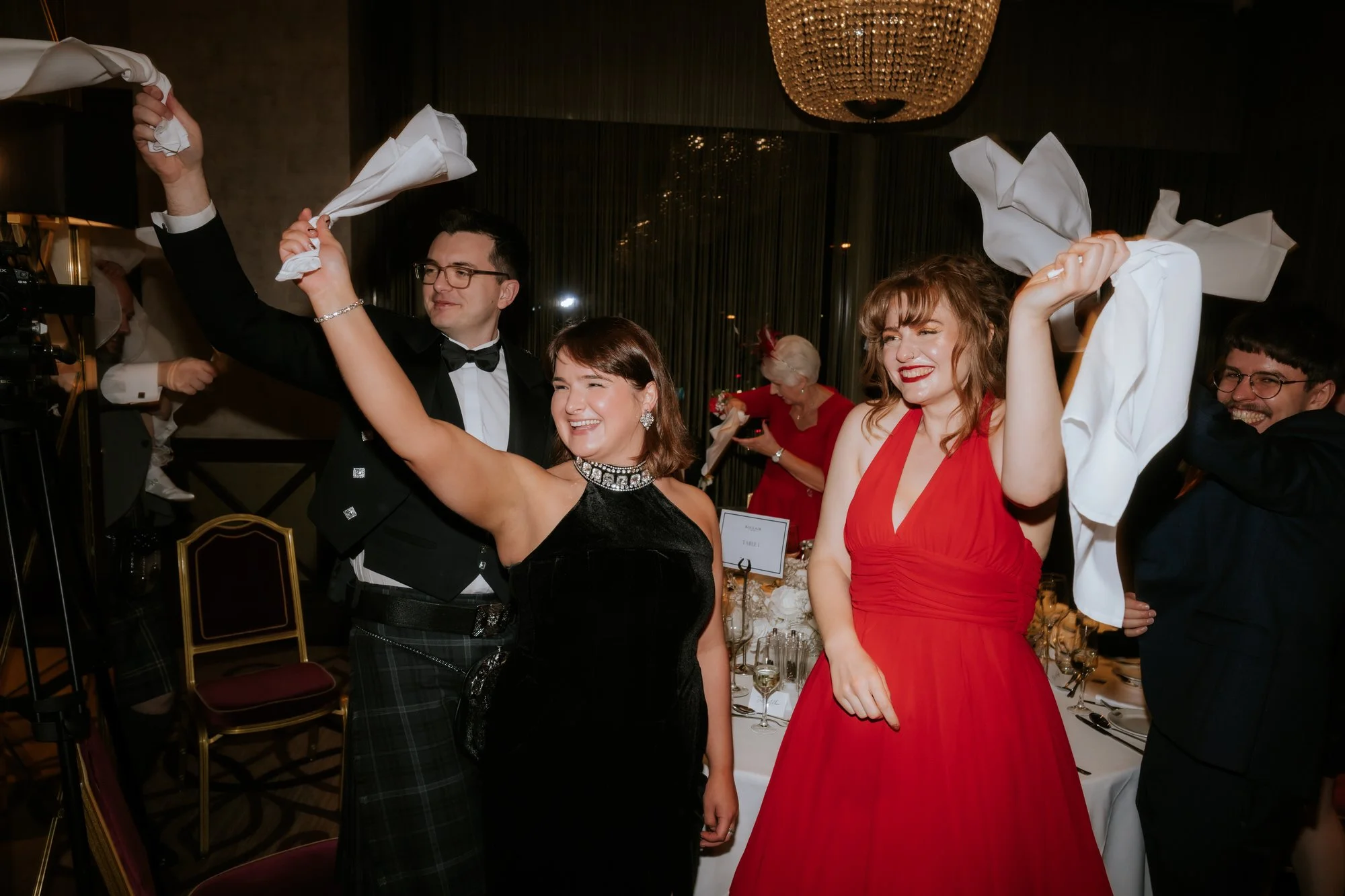 Wedding guests cheering and waving white napkins at the reception