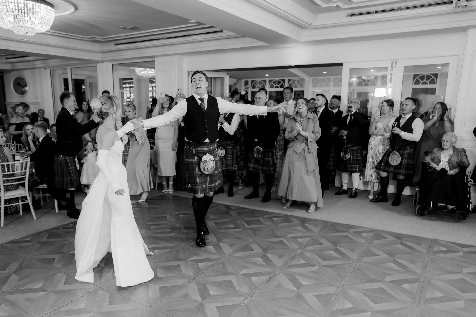 Fiona and Connor celebrating on the dance floor surrounded by guests.