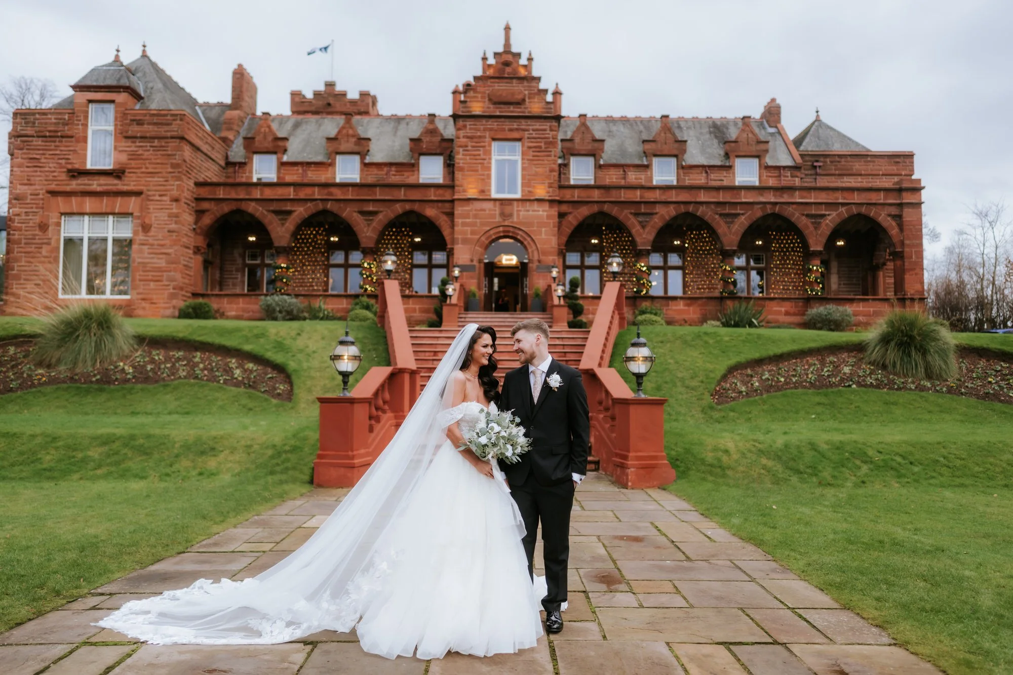 Bride and groom standing outside Boclair House with the red sandstone building behind them