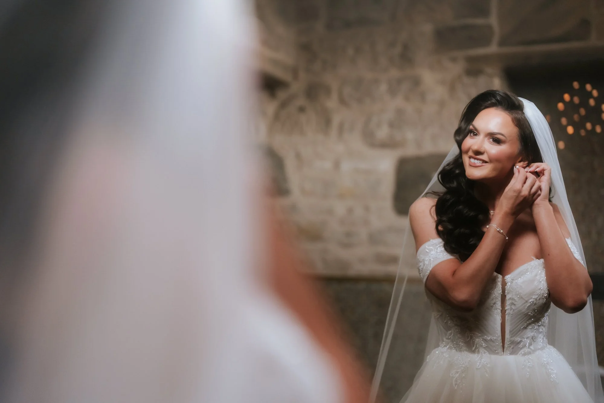 Bride reflected in a mirror while putting on an earring