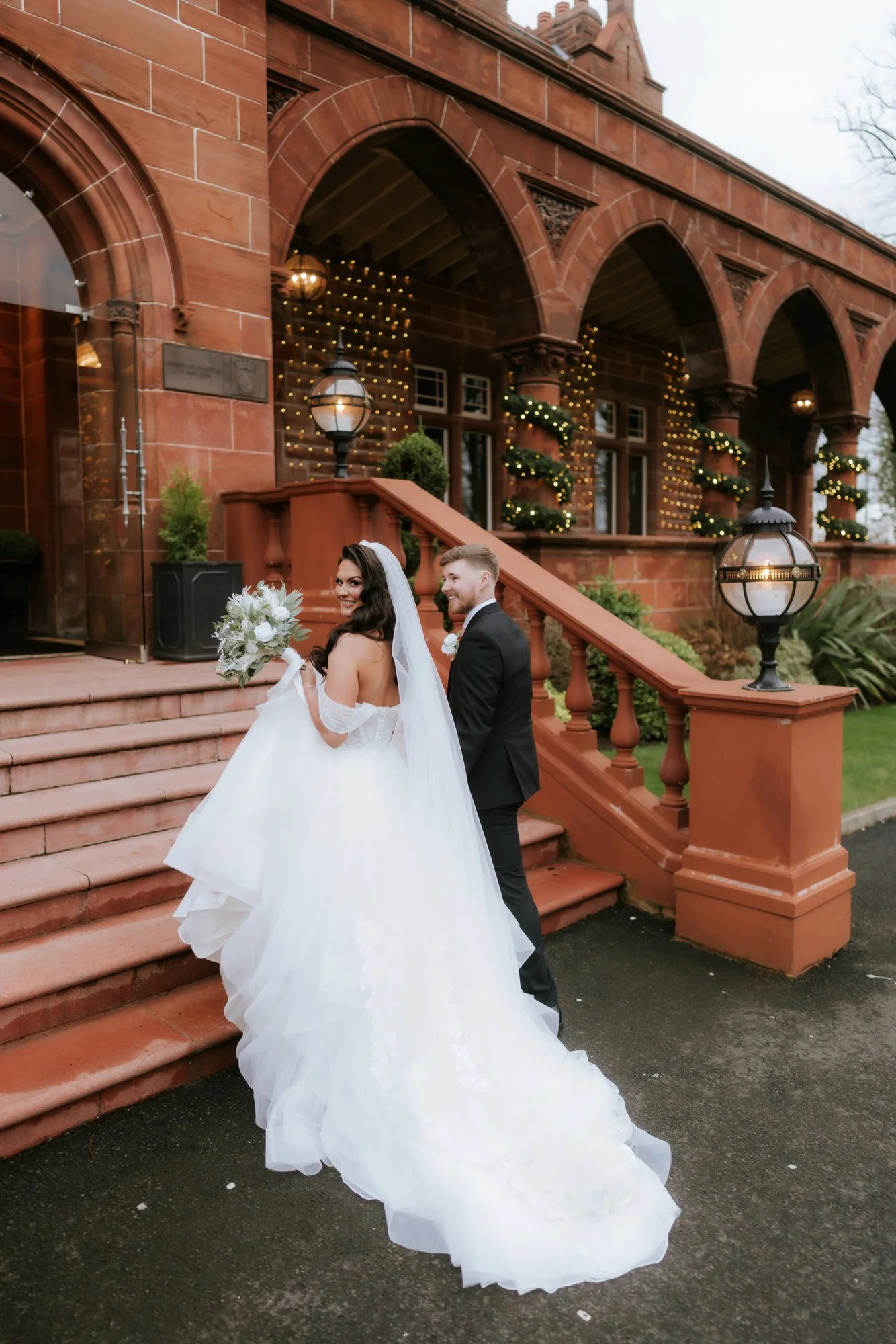 Bride and groom looking back as they climb the steps at Boclair House