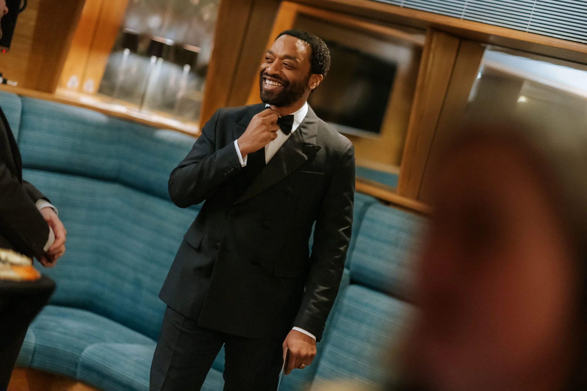 Chiwetel Ejiofor adjusting his bow tie backstage at the 2025 BAFTA Film Awards.