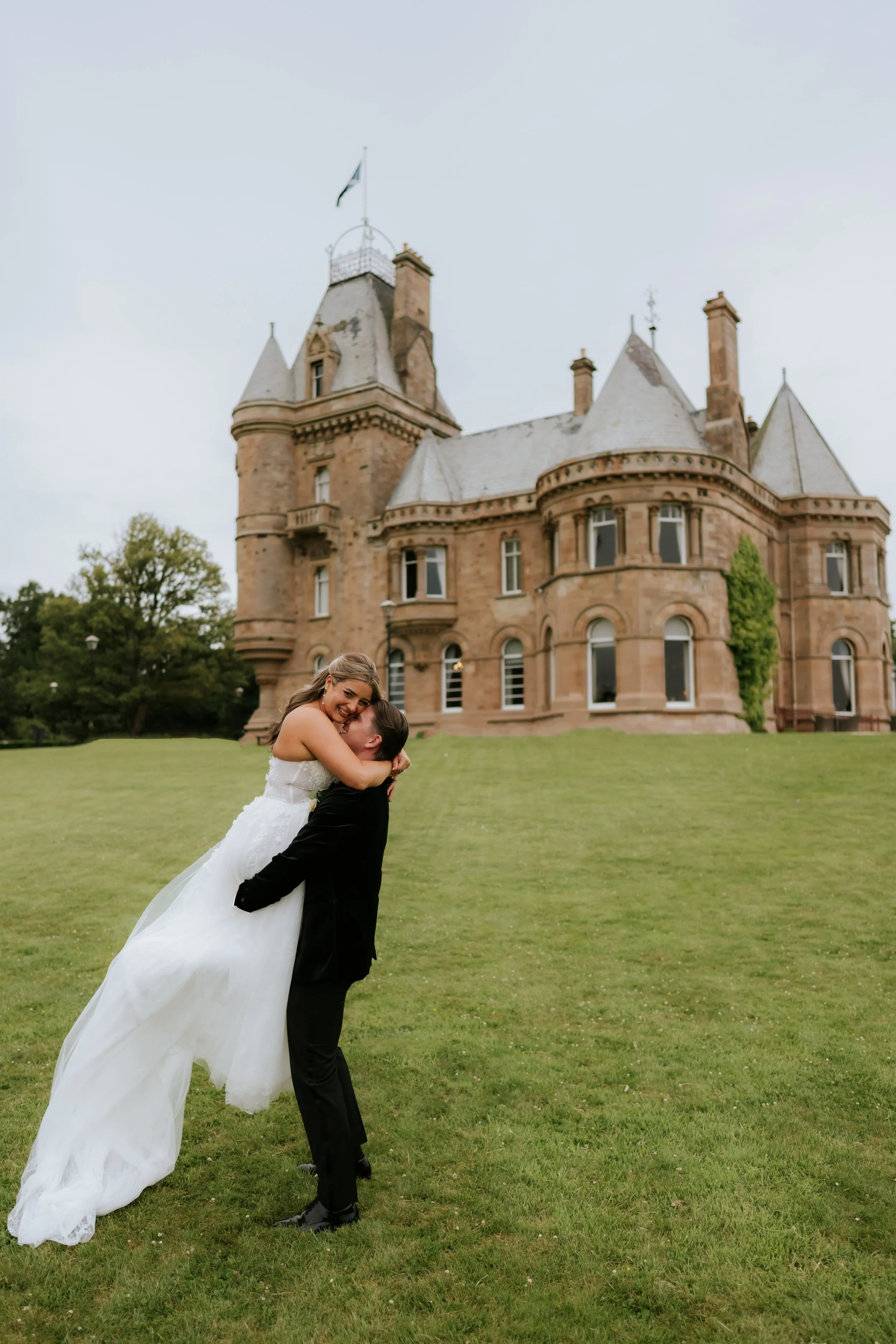 Emma and Frazer embracing on the lawn in front of Cornhill Castle.