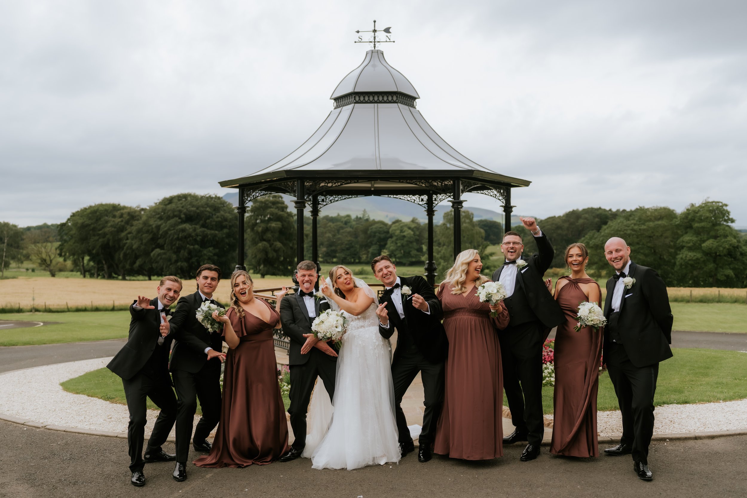 Emma and Frazer celebrating with their wedding party beside Cornhill Castle’s bandstand.