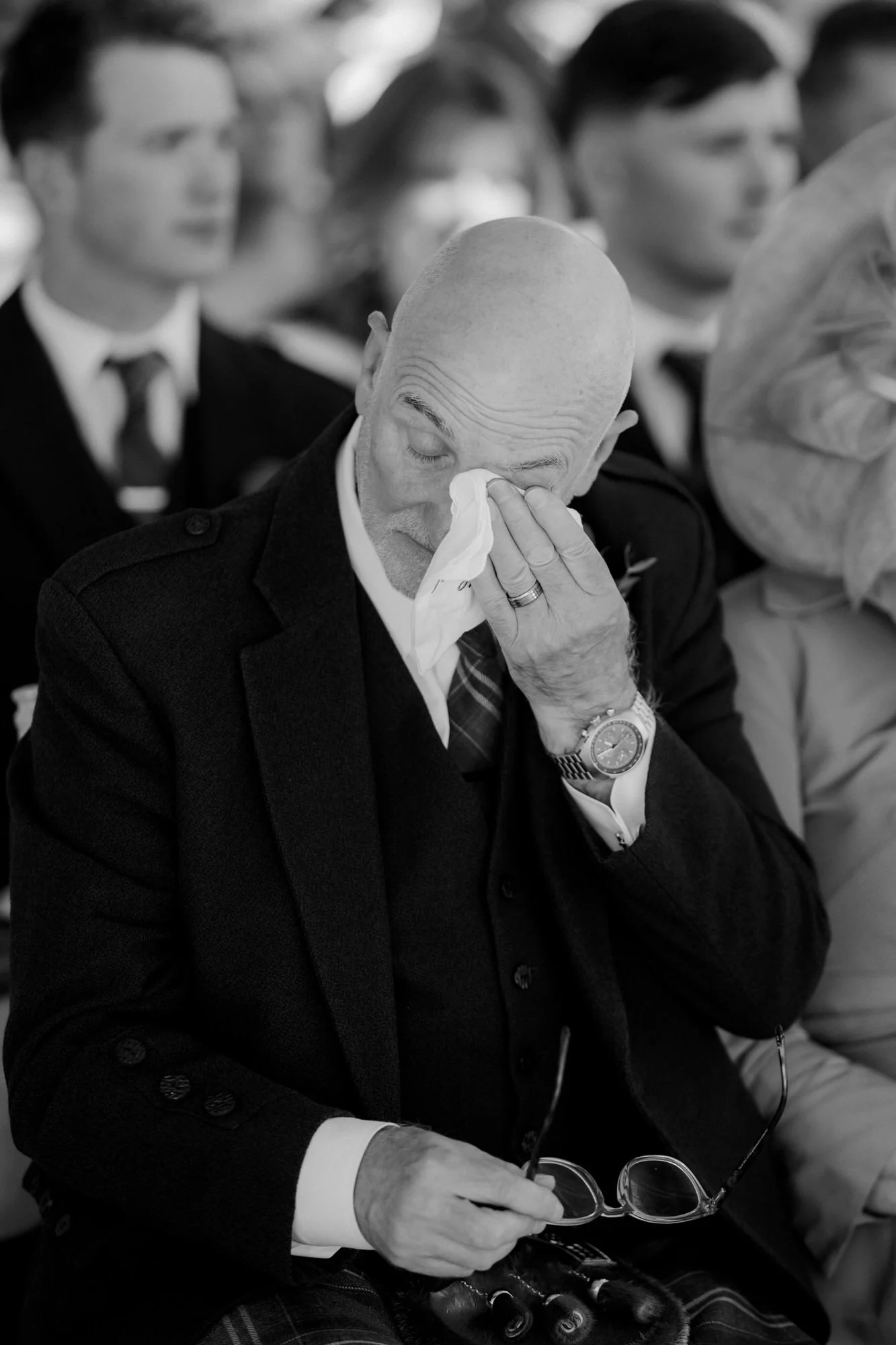 An emotional guest wiping away a tear during the wedding ceremony.