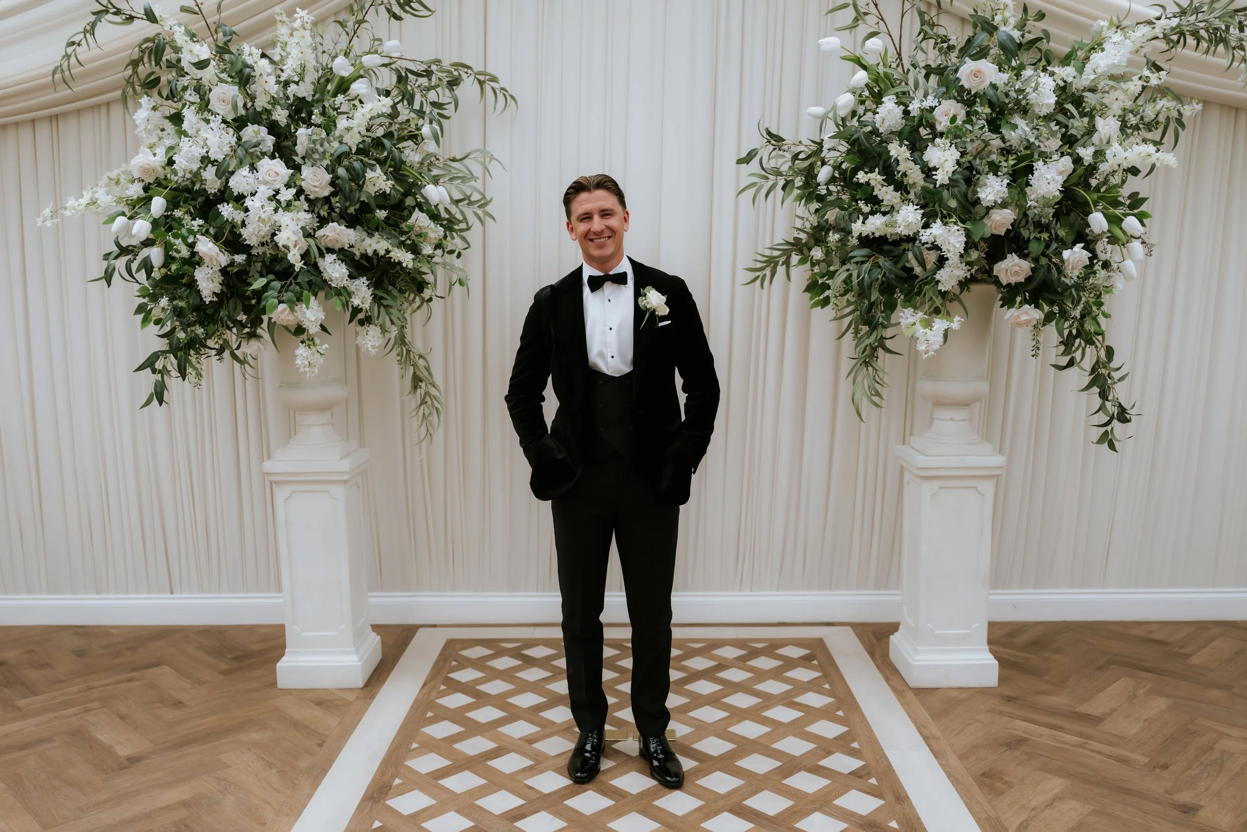 Frazer standing between white floral displays in the new wedding pavilion.