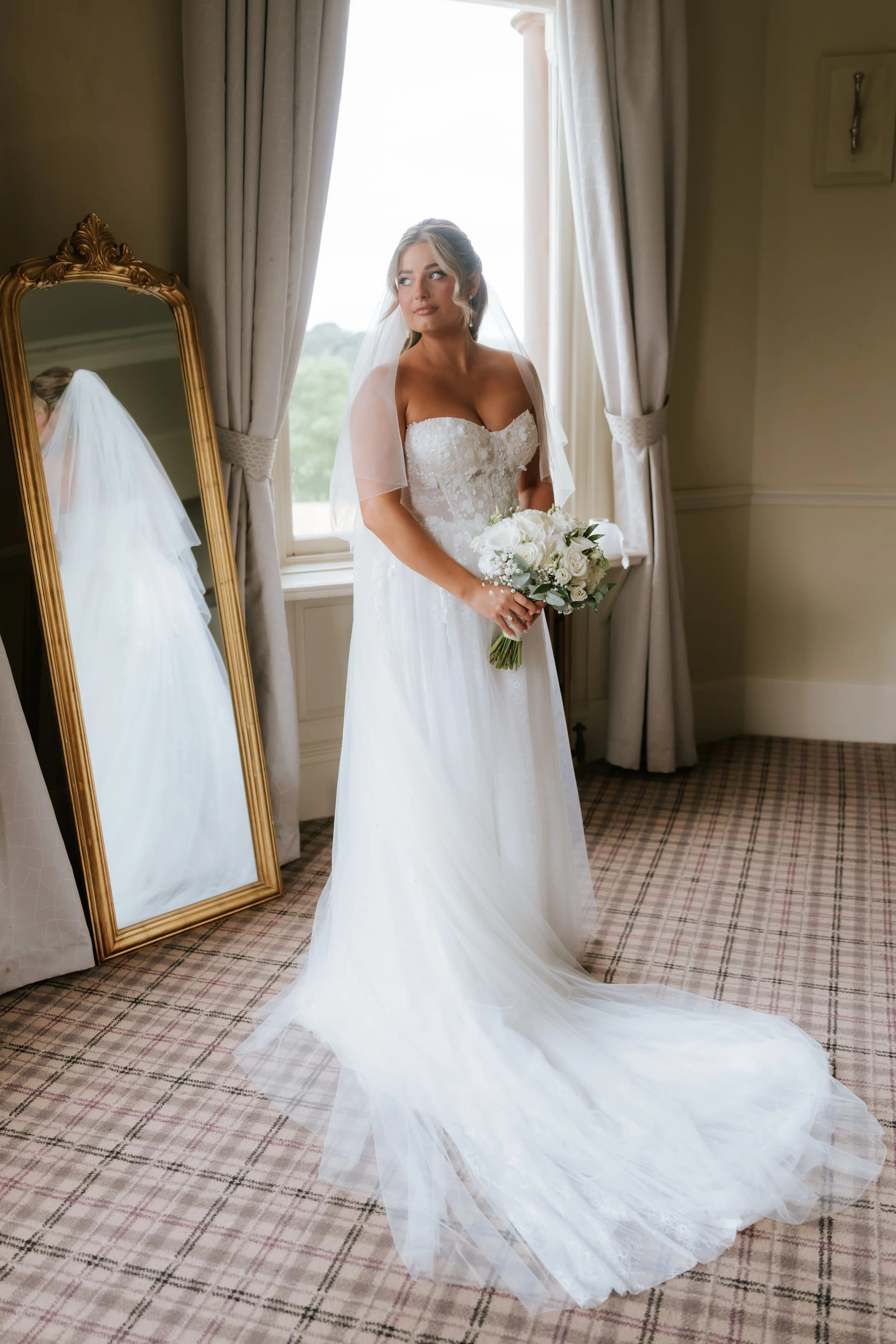 Emma holding her bouquet beside a window inside Cornhill Castle.